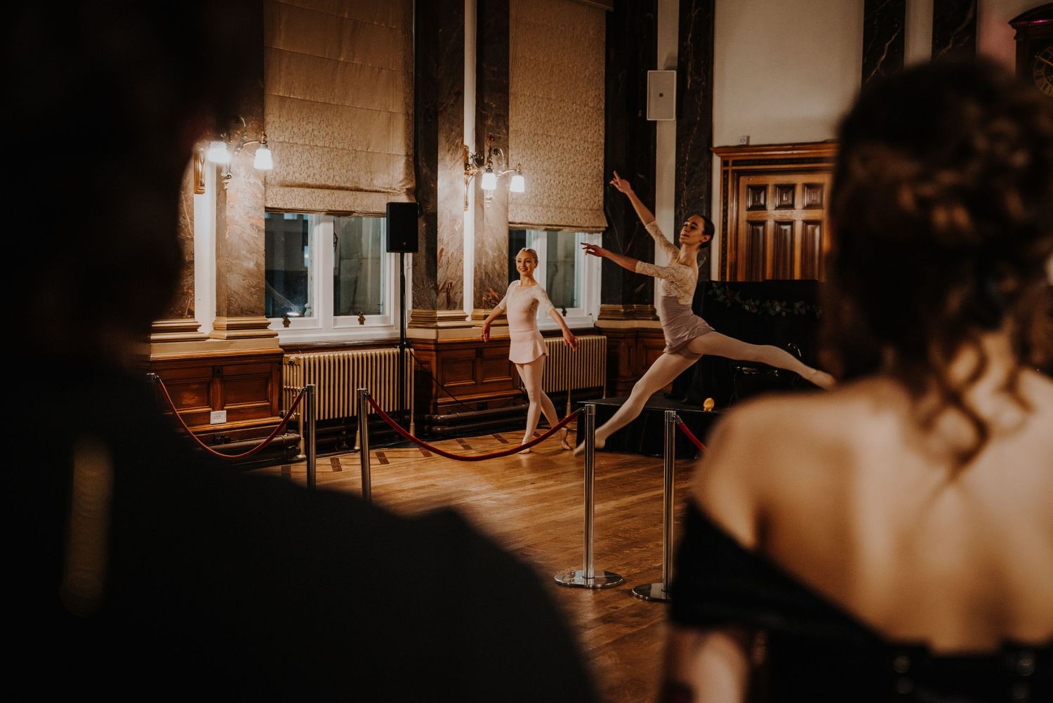 Ballet dancers perform their positions and movements on a wooden floor at a fantasy ball.