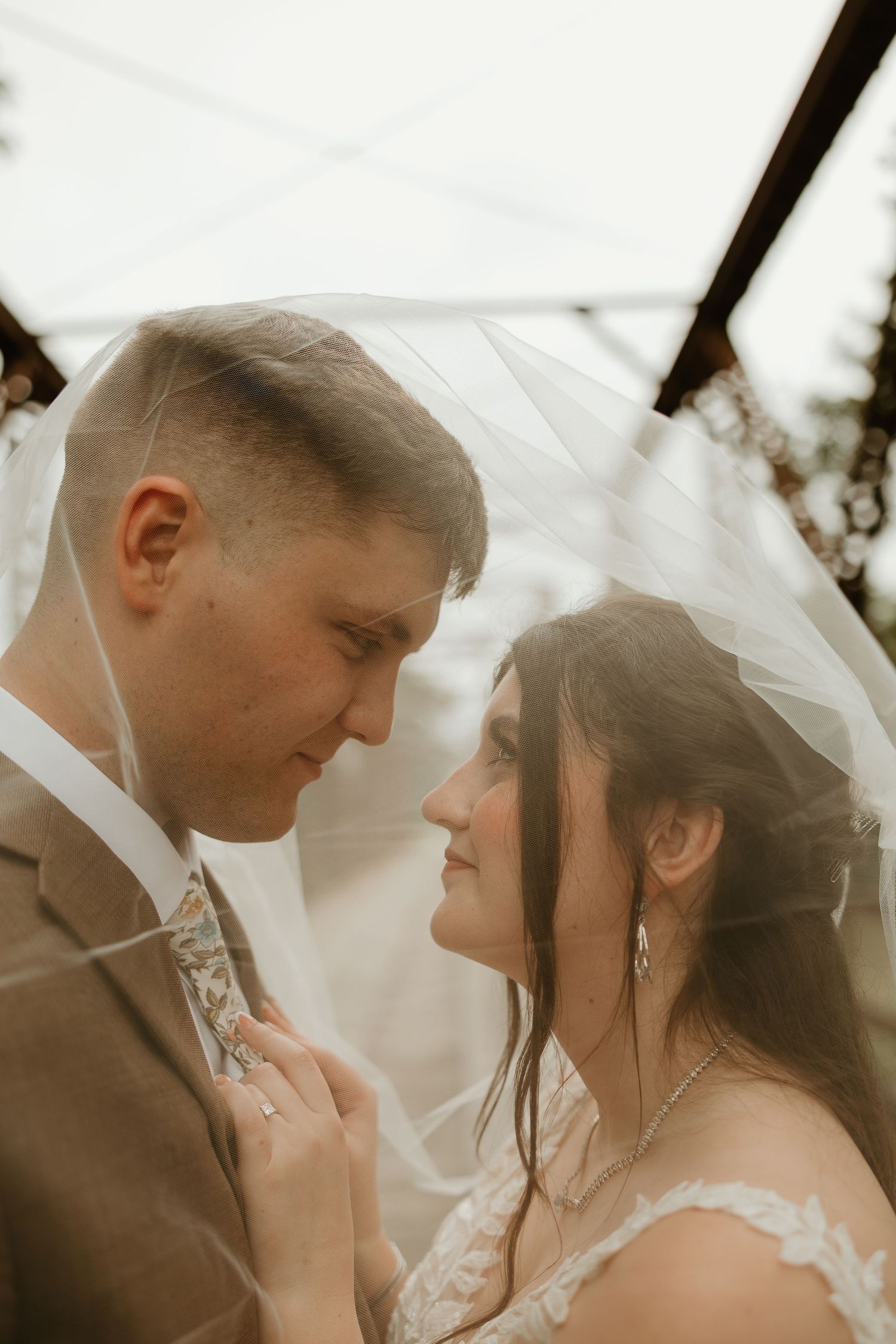 A romantic wedding couple shares an intimate moment under a flowing white veil in a series of four connected photos.