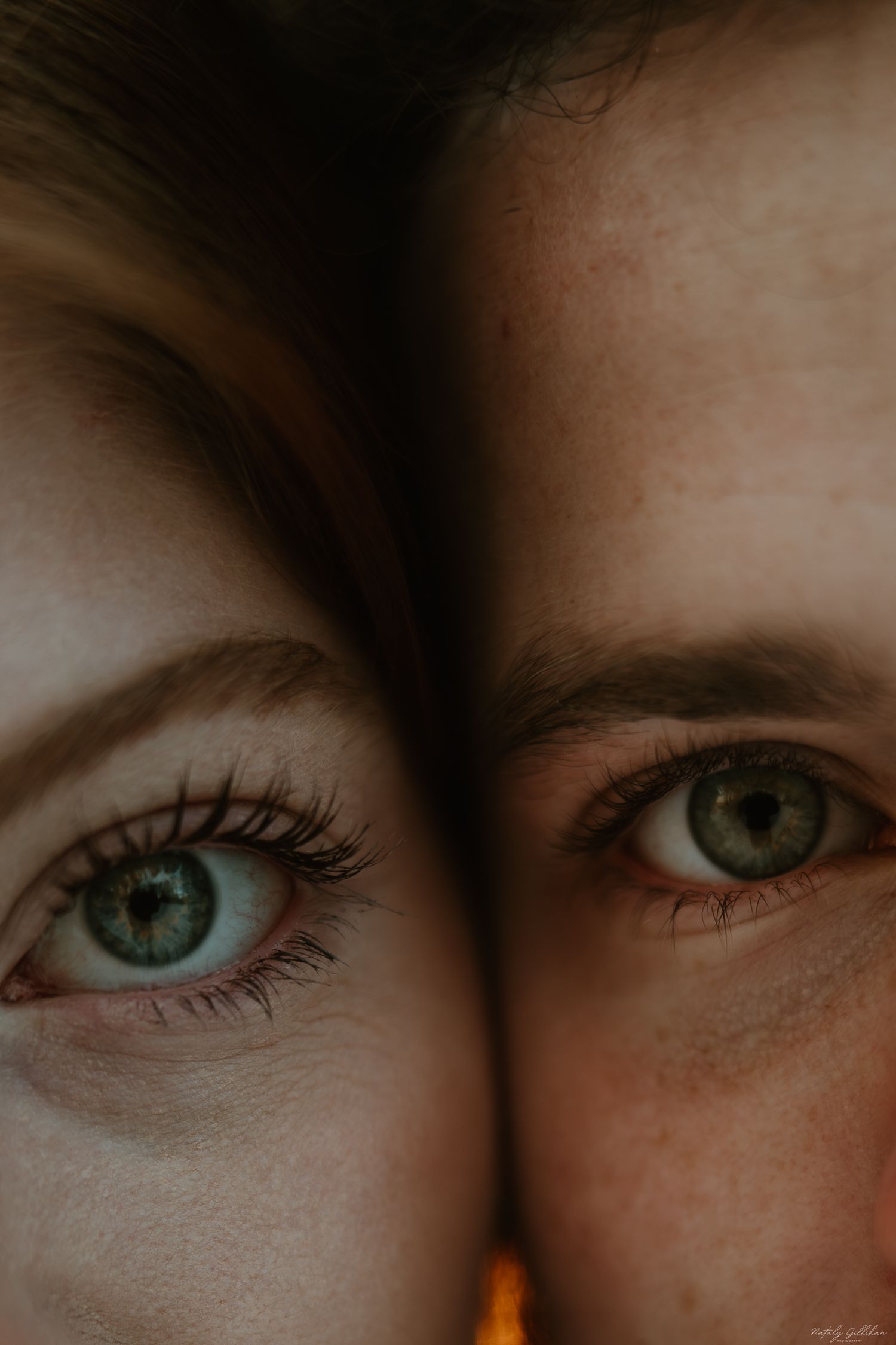 Extreme close-up of two green eyes side by side in dramatic lighting.