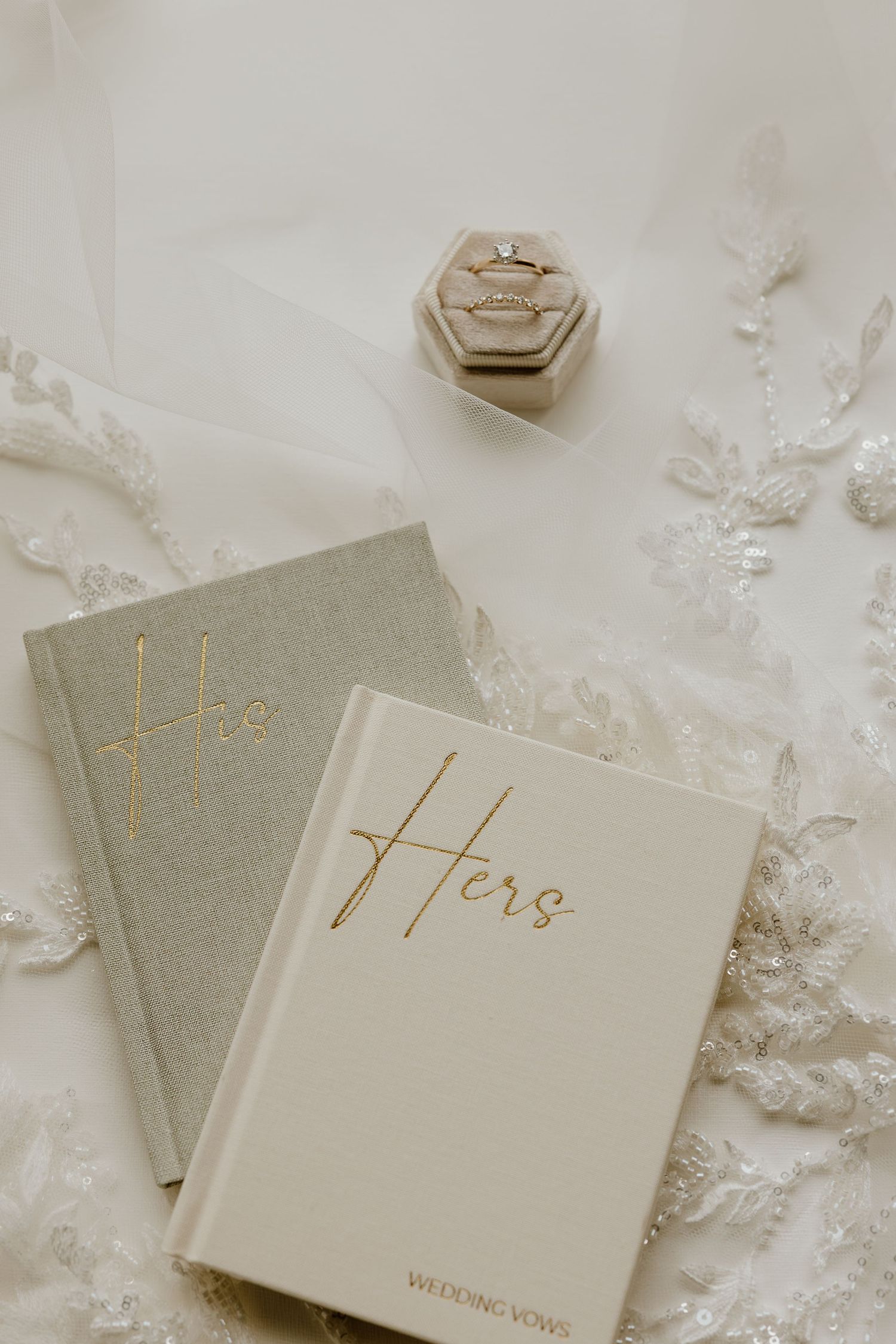 Minimalist wedding vow books in soft gray and white with elegant gold lettering arranged on a textured surface.