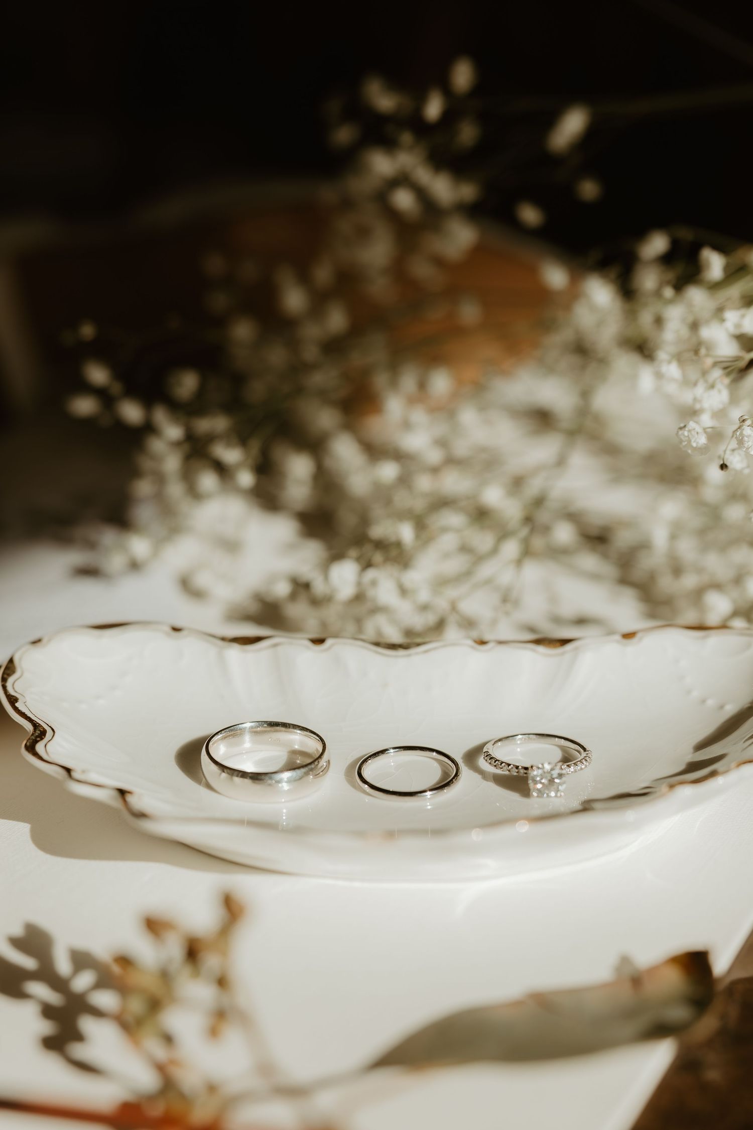 Wedding rings displayed on a white surface surrounded by delicate baby's breath flowers.