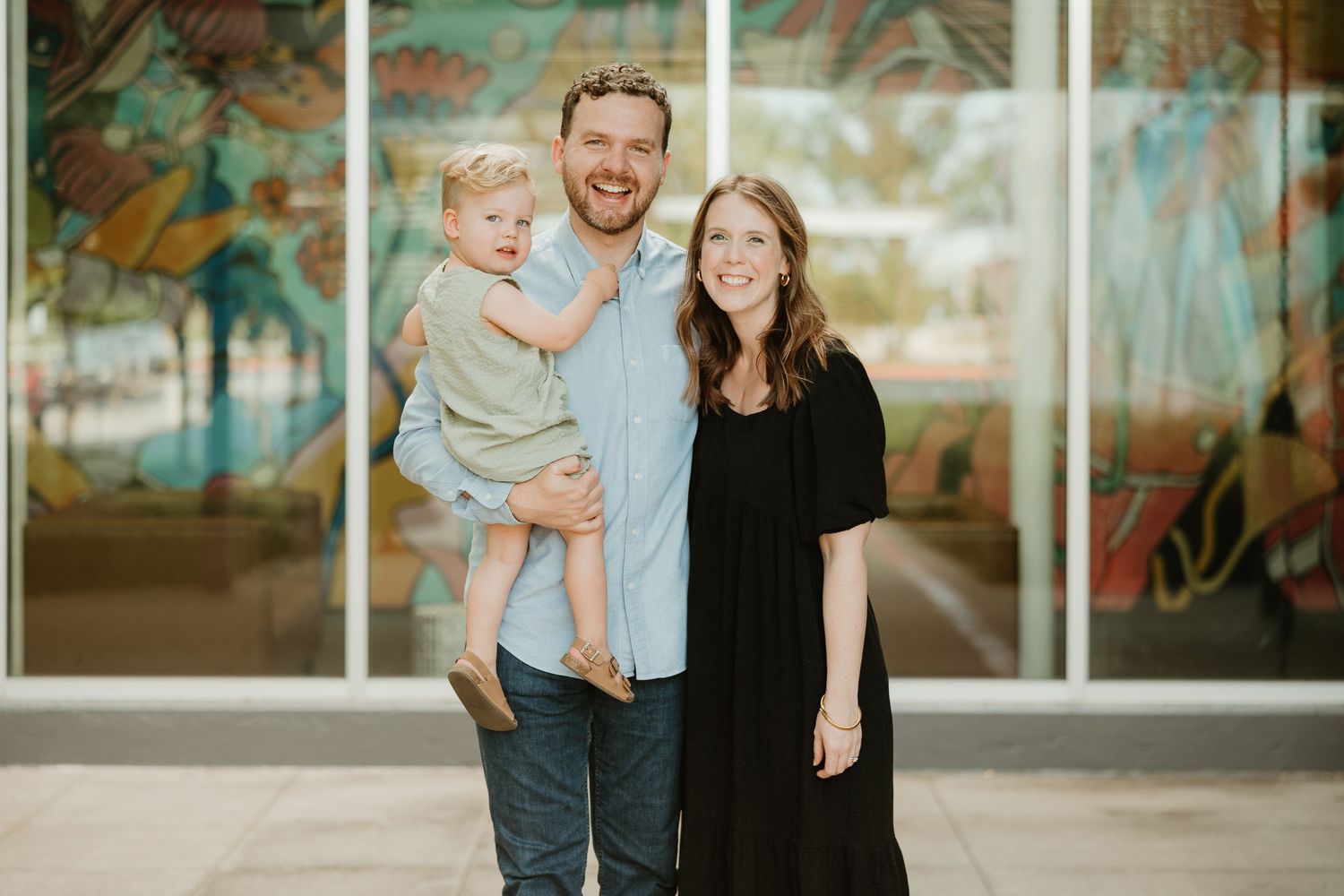 Family wearing coordinated blue and white outfits poses for outdoor photo sessions against floral backdrop.