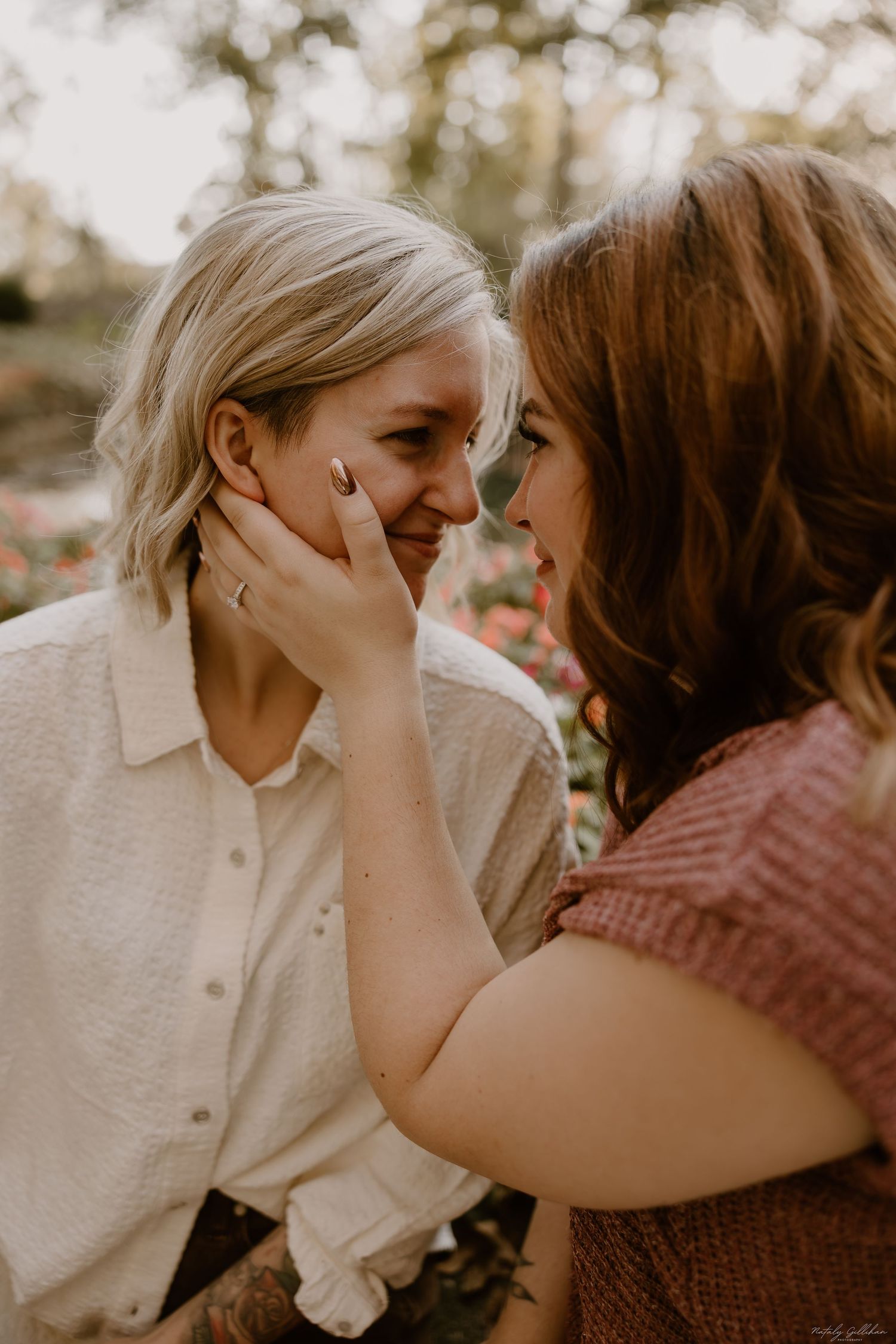 Two people share an intimate moment outdoors with soft natural lighting and warm earth tones in their clothing.