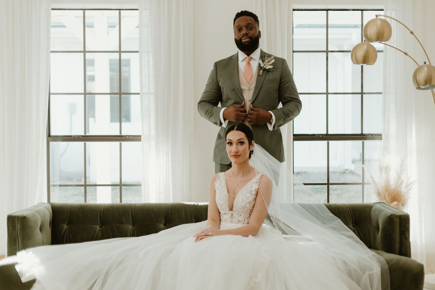 A bride and groom share an intimate moment in a bright, modern wedding venue with large windows.