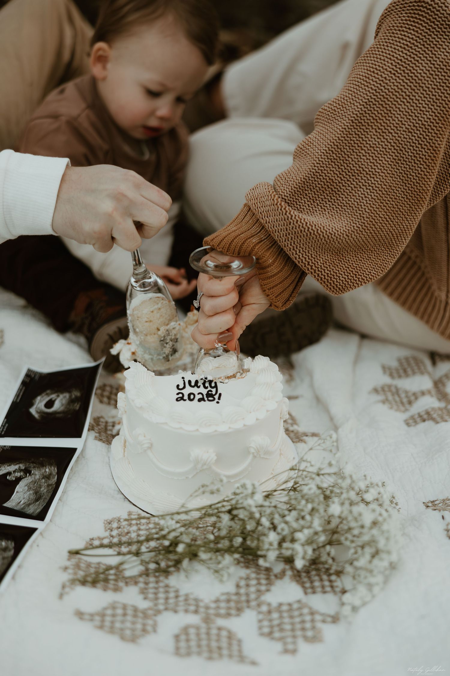 Decorating a small white cake with ultrasound photos visible in the scene.