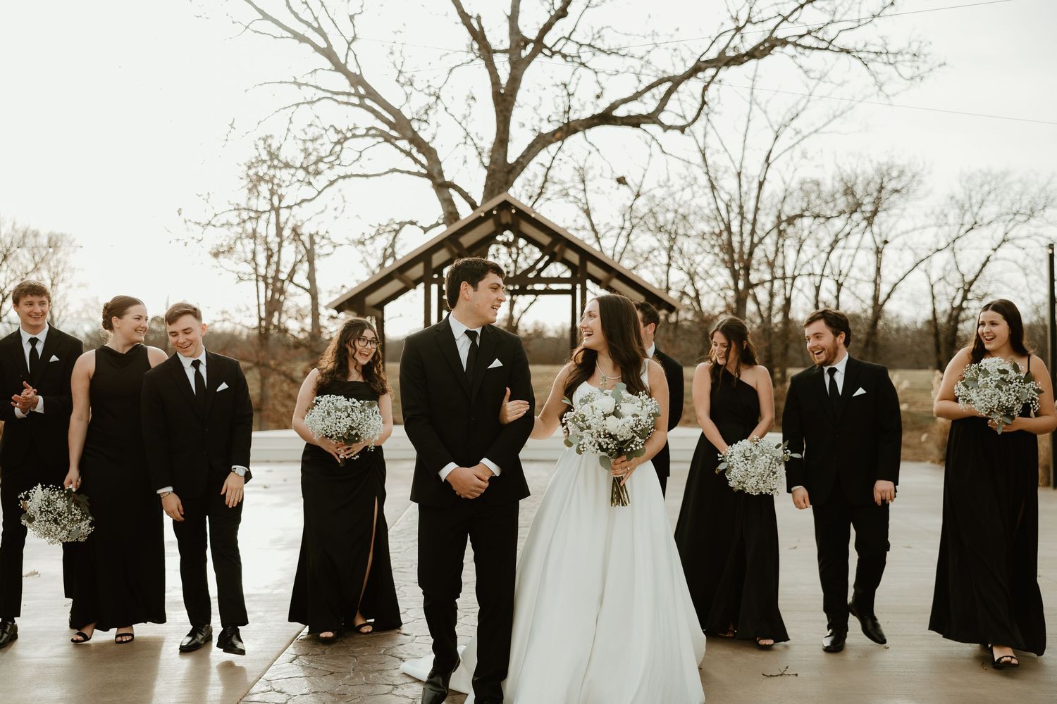Wedding party in black and white formal attire poses outdoors during winter.
