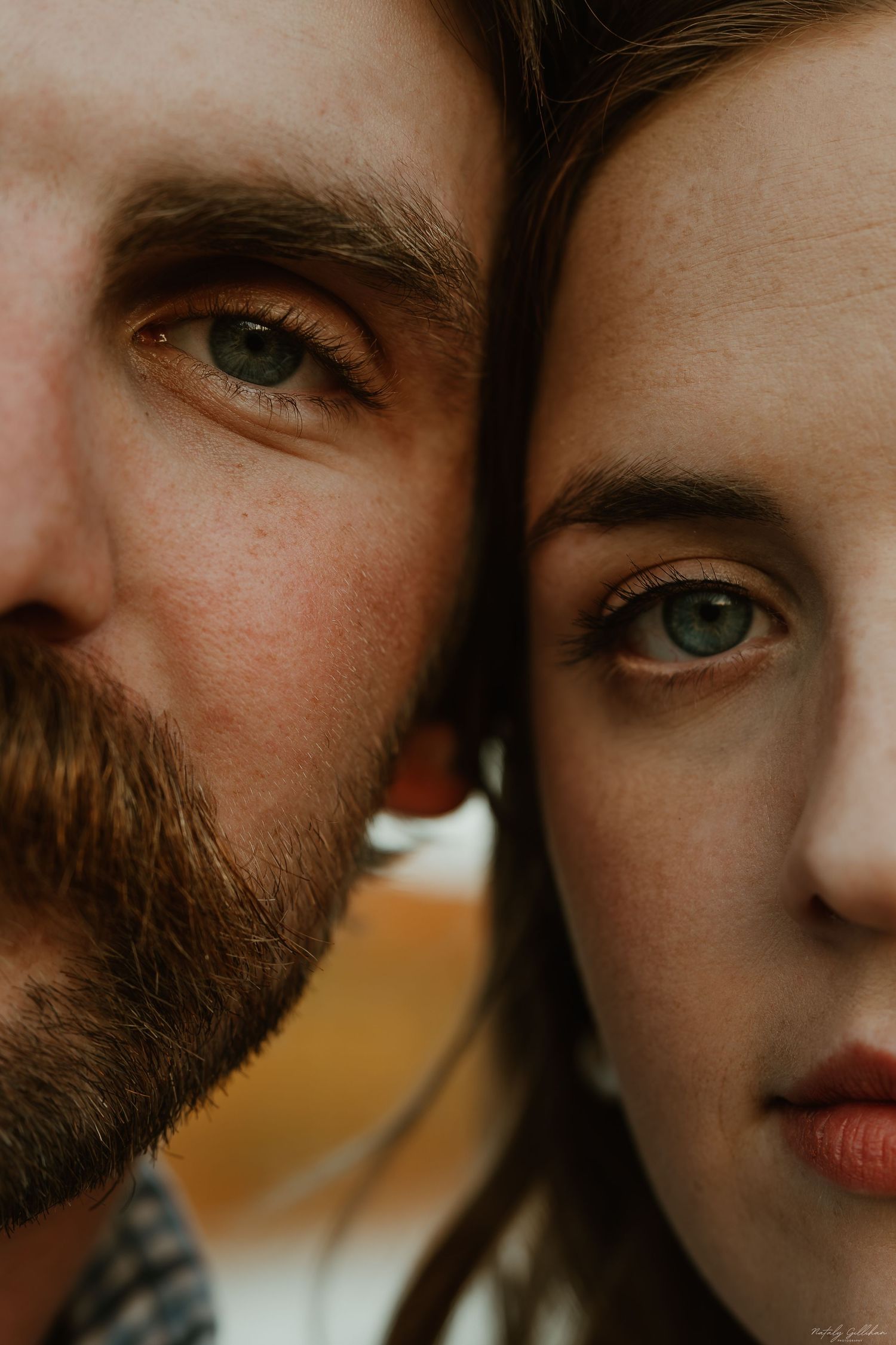 Close-up portrait showing two faces side by side with striking green eyes and warm lighting.
