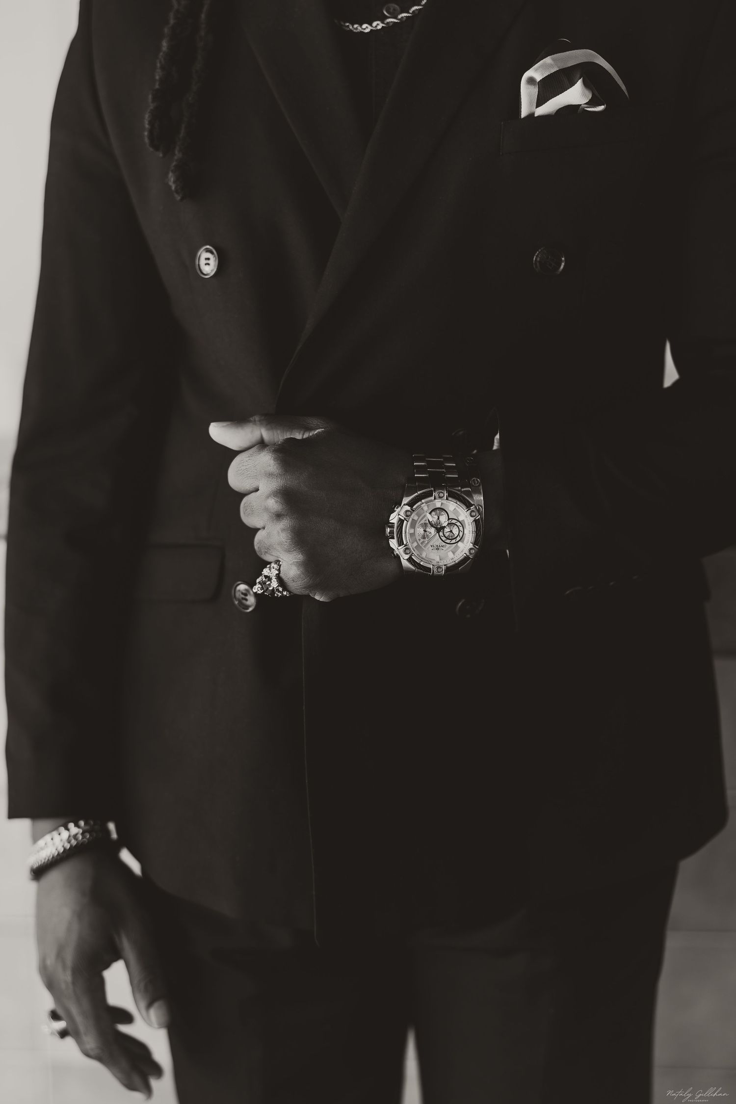 Close-up view of a luxury watch worn with an elegant black suit and pocket square.
