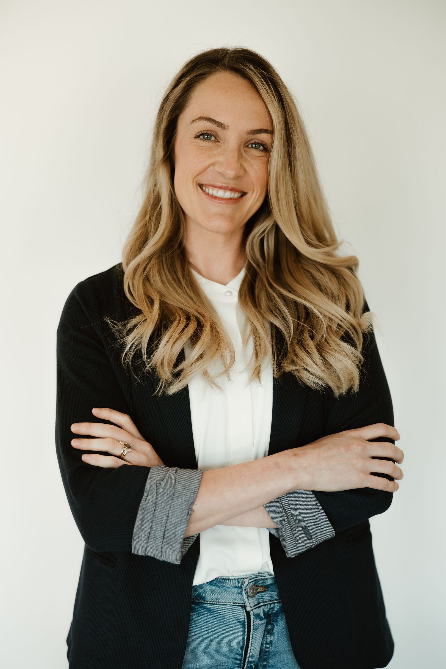Professional headshot series showing classic business casual style with black blazer, white top and denim against white background.
