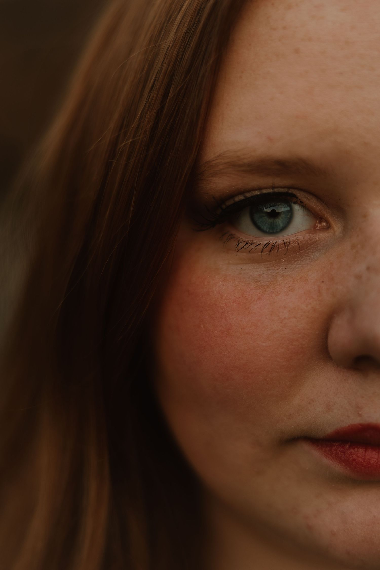 A close-up photo series showing different angles and fragments of a face with striking blue eyes and freckles.