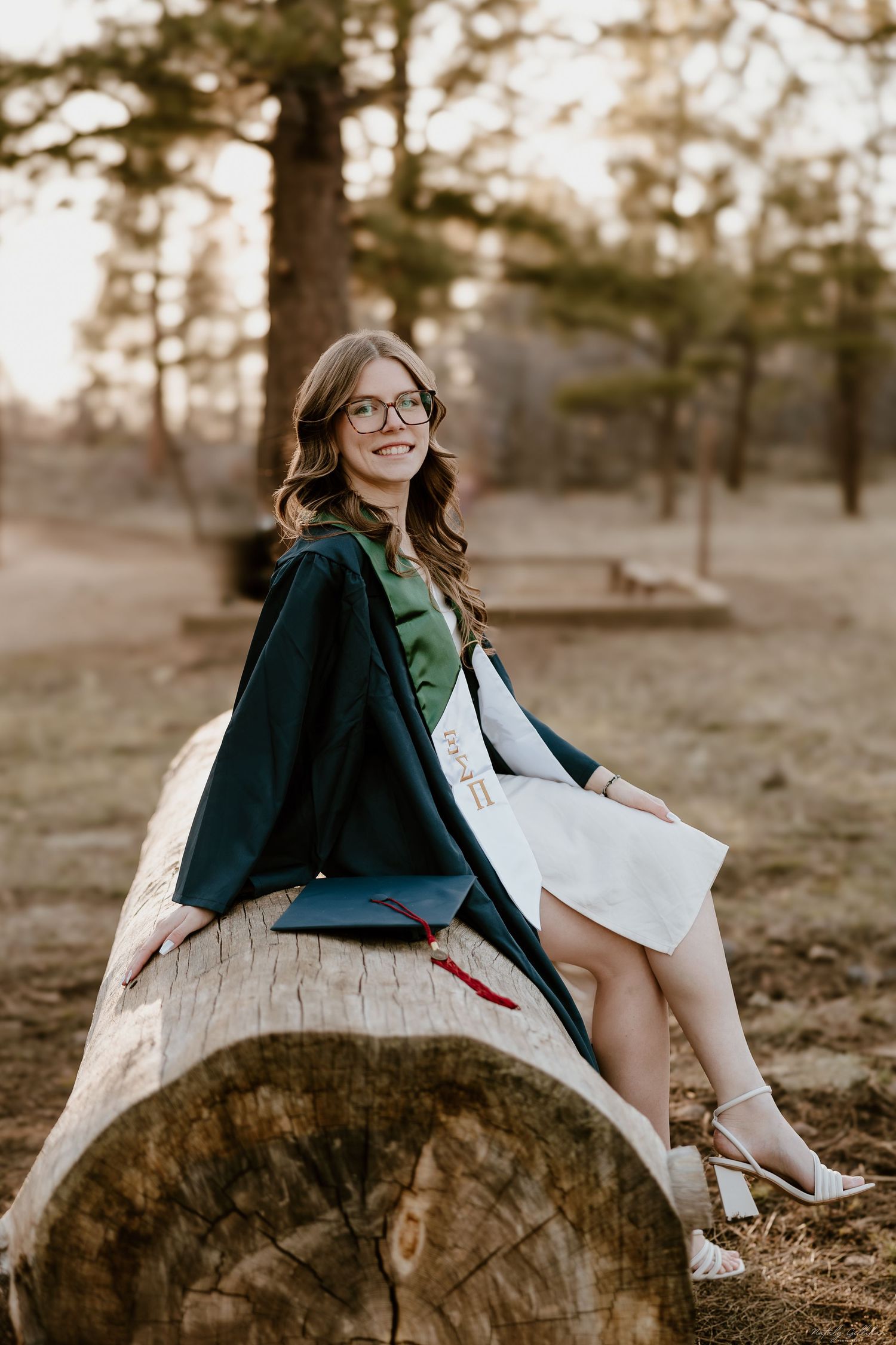 Three photos of someone in a dark blazer and white dress sitting casually on a large tree stump at sunset.