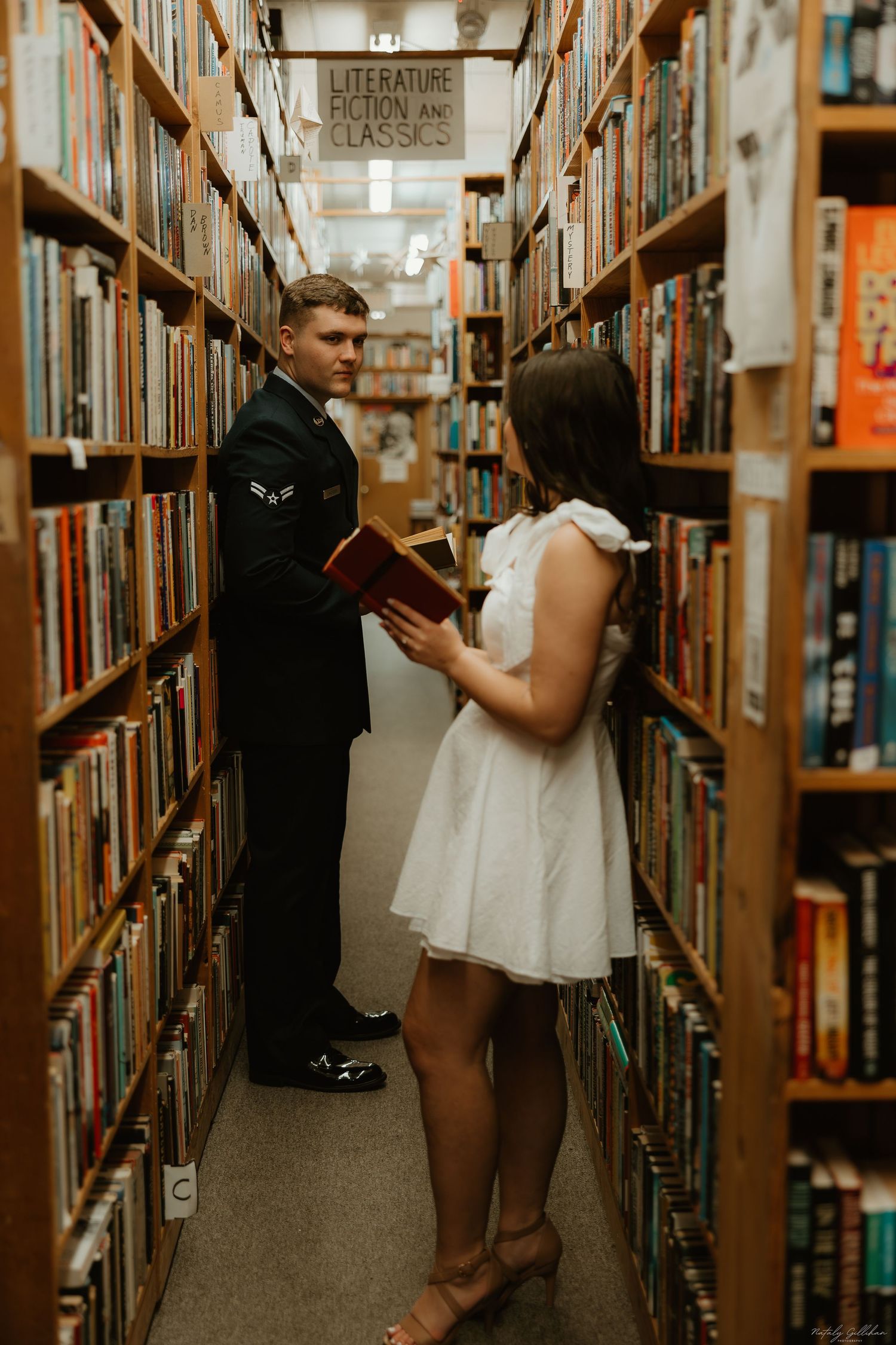 Couple browsing books together in a library aisle.