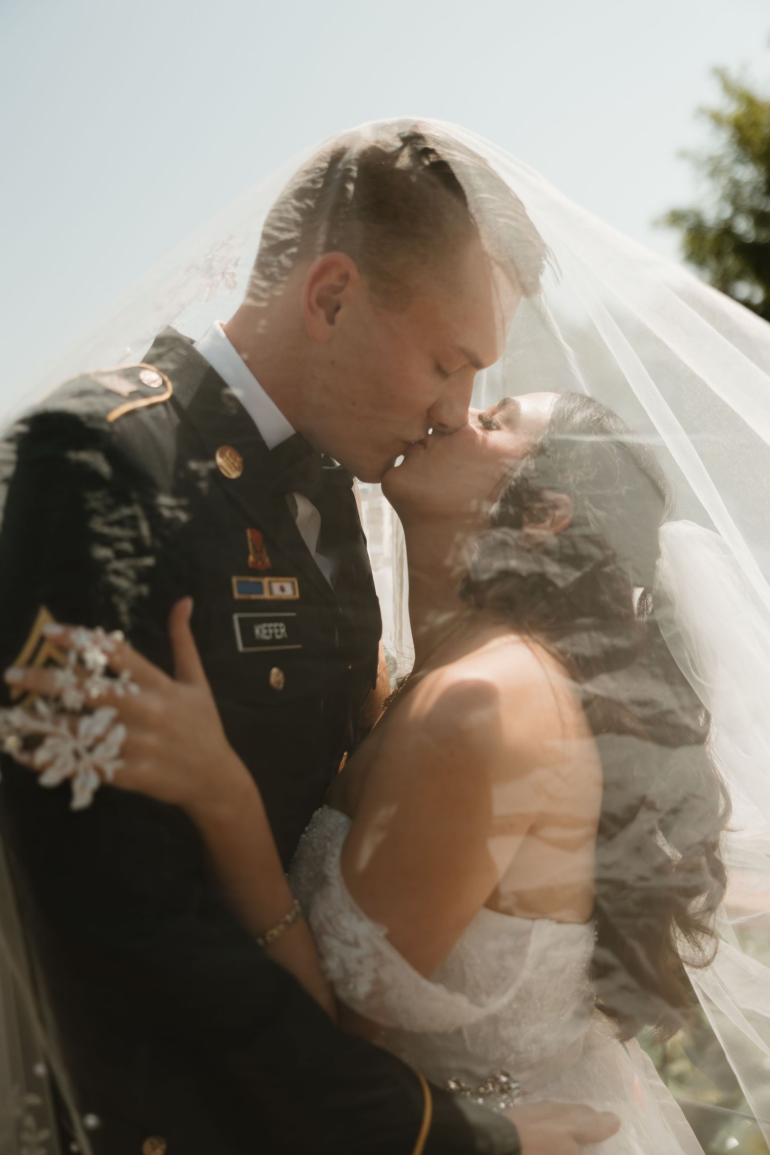 A romantic wedding couple shares intimate moments under a flowing veil in a series of candid photographs.