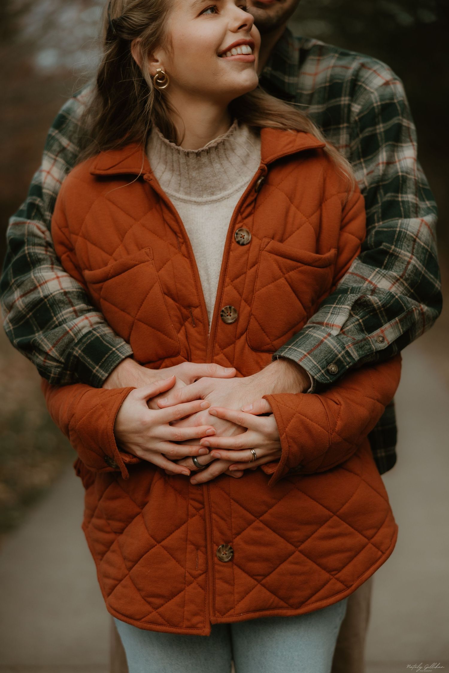 A cozy autumn embrace featuring a rust-colored quilted jacket and plaid flannel sleeves in warm fall lighting.