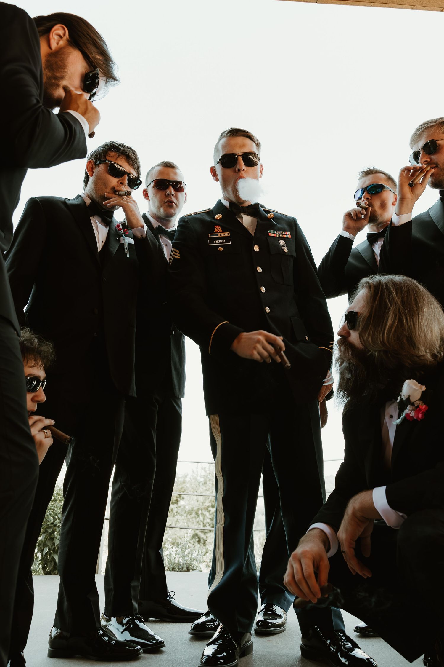 Groomsmen in black suits and sunglasses pose together in a casual moment during a wedding photoshoot.