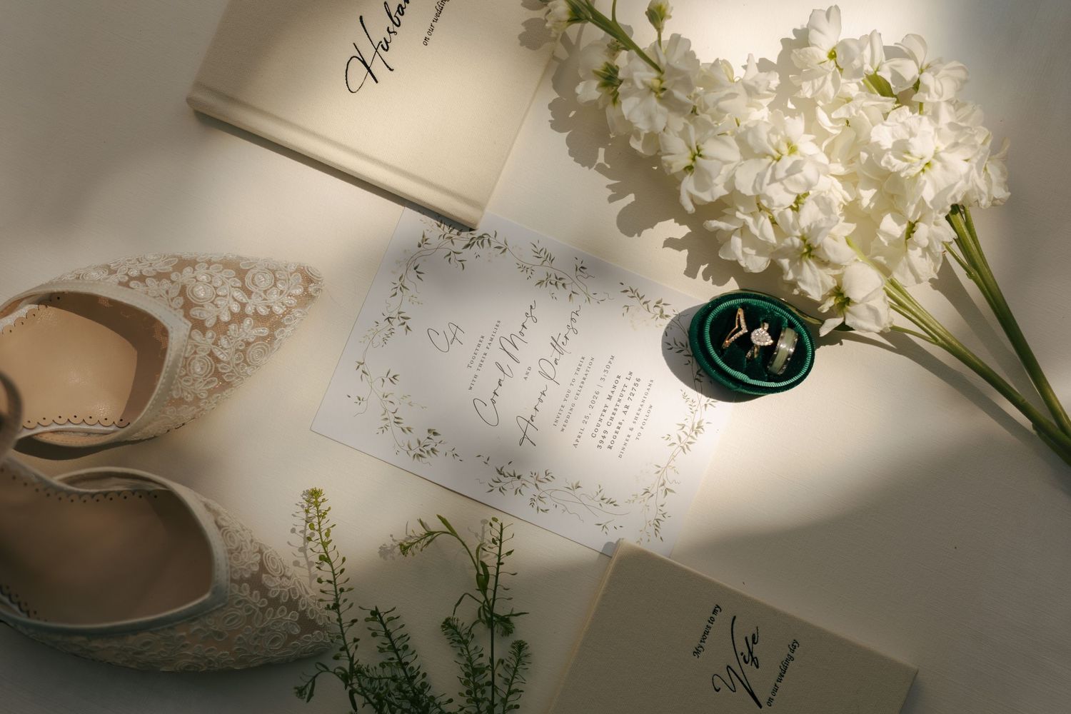 Elegant wedding flat lay with lace heels, floral invitation, rings in green dish, and white hyacinth blooms.
