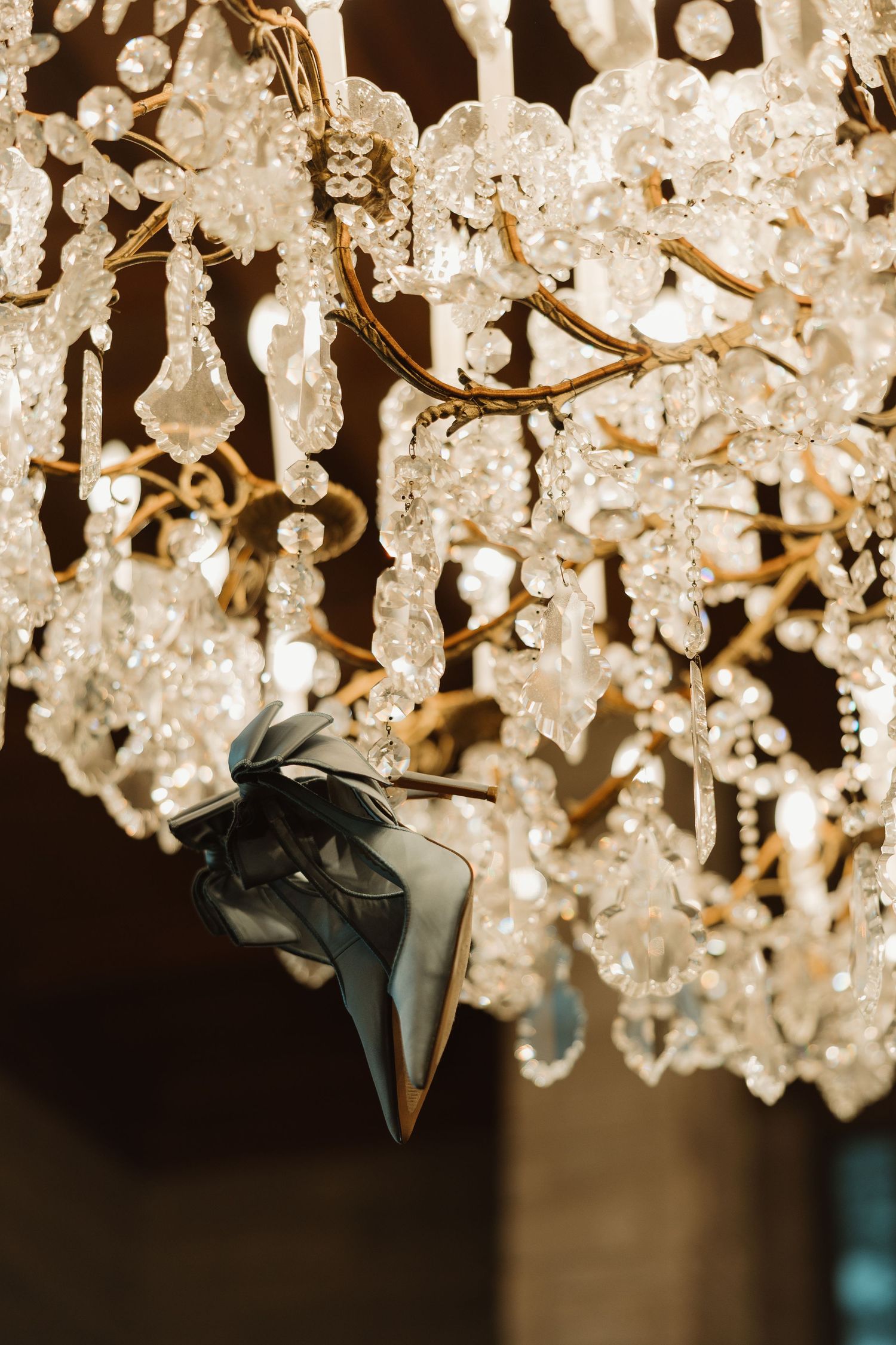 Crystal chandelier details with sparkling glass droplets hanging against a dark background.