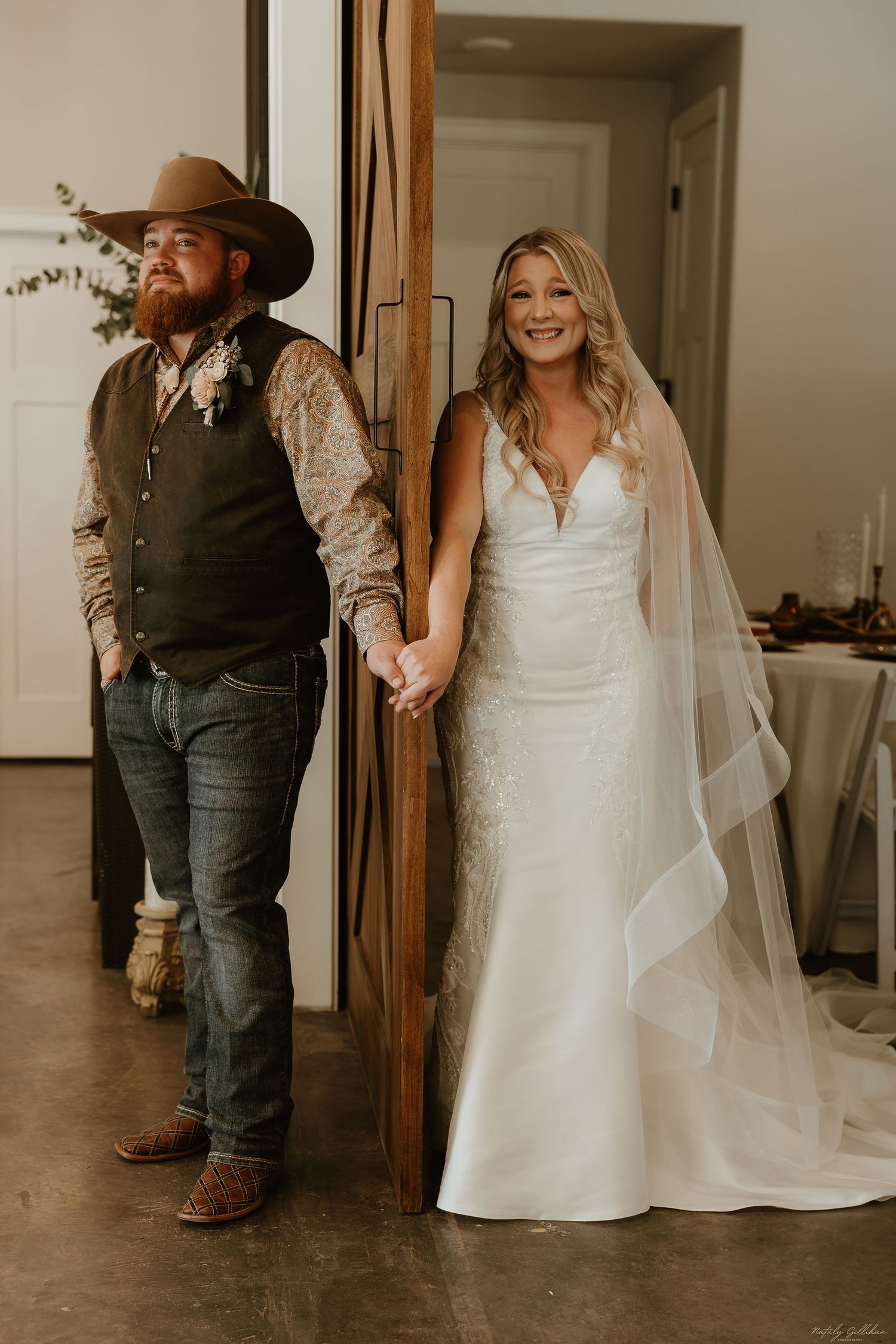 A couple shares a heartfelt first look moment before their wedding, with the bride in white and groom in western attire.
