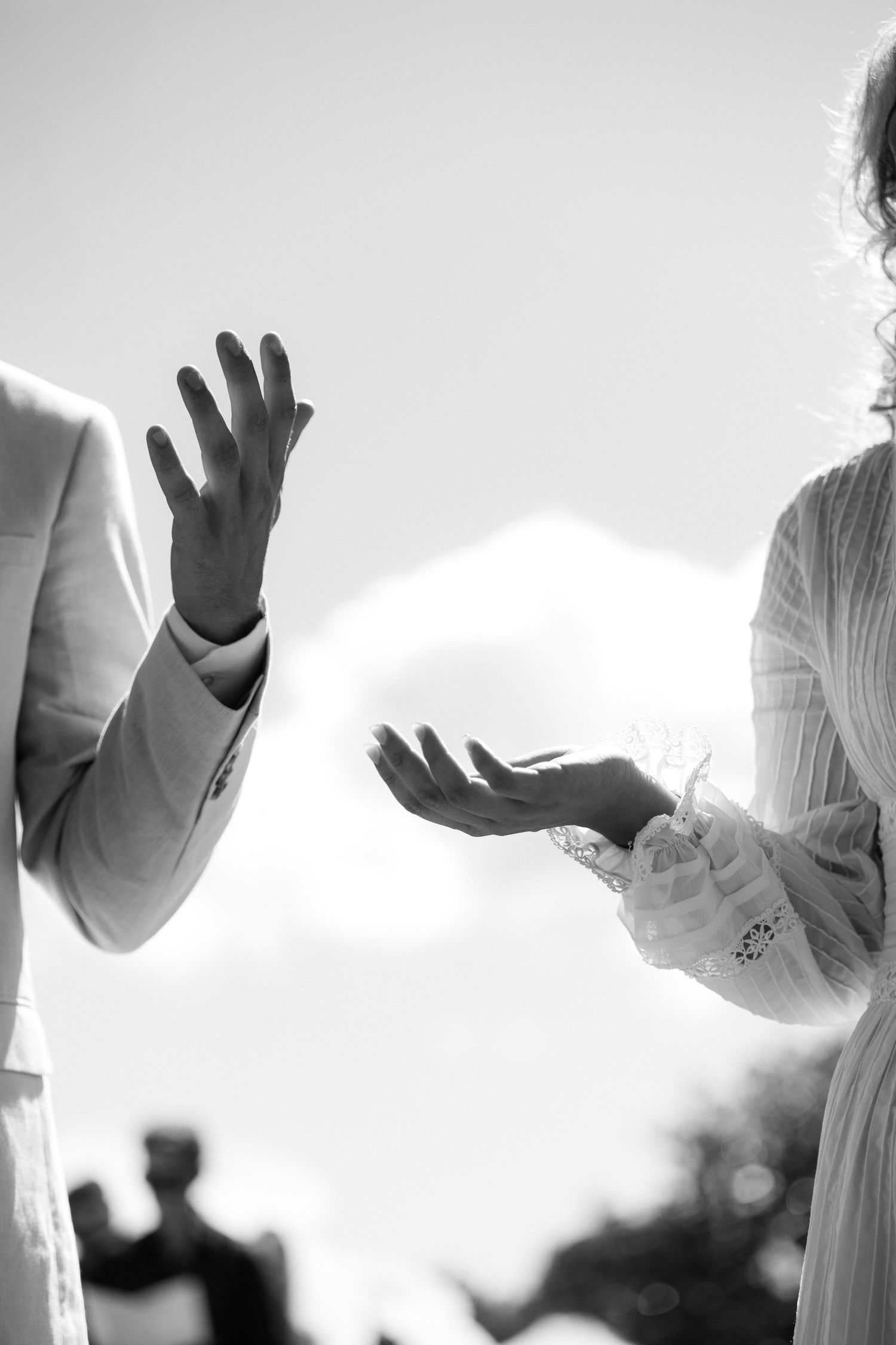 Artistic black and white photo of raised hands against bright sunlight. Auckland Wedding Photographer and videographer