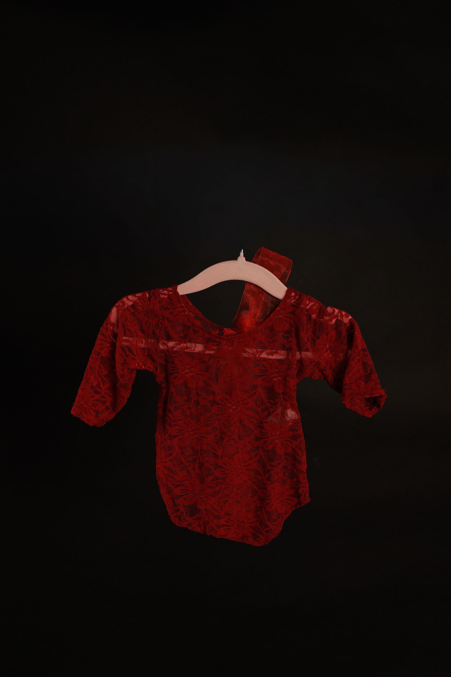 A sequence of four red velvet sweaters or shirts shown in silhouette against a black background.