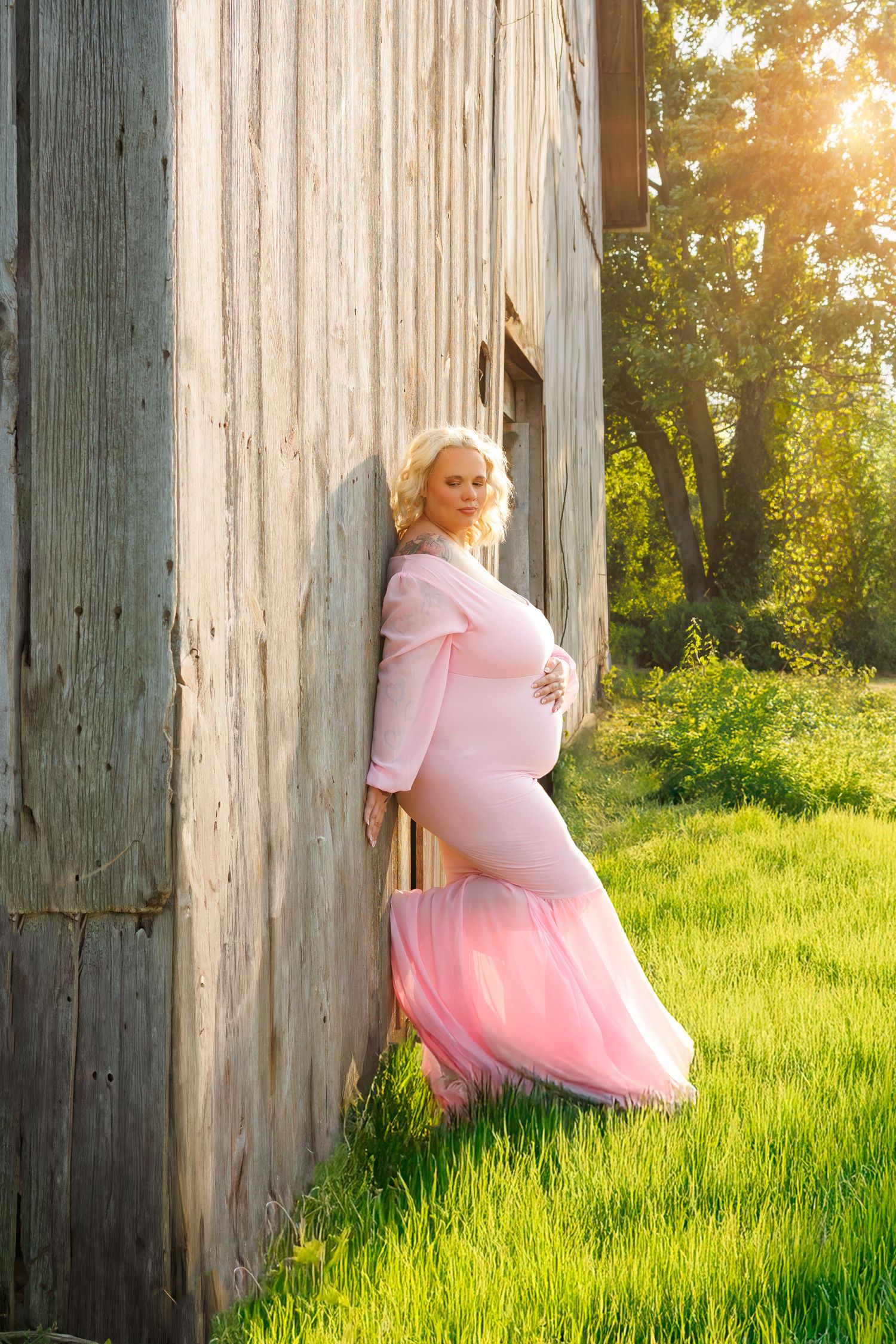 Whimsical pink dress photo series against rustic wood pillars and sunlit grass at golden hour.