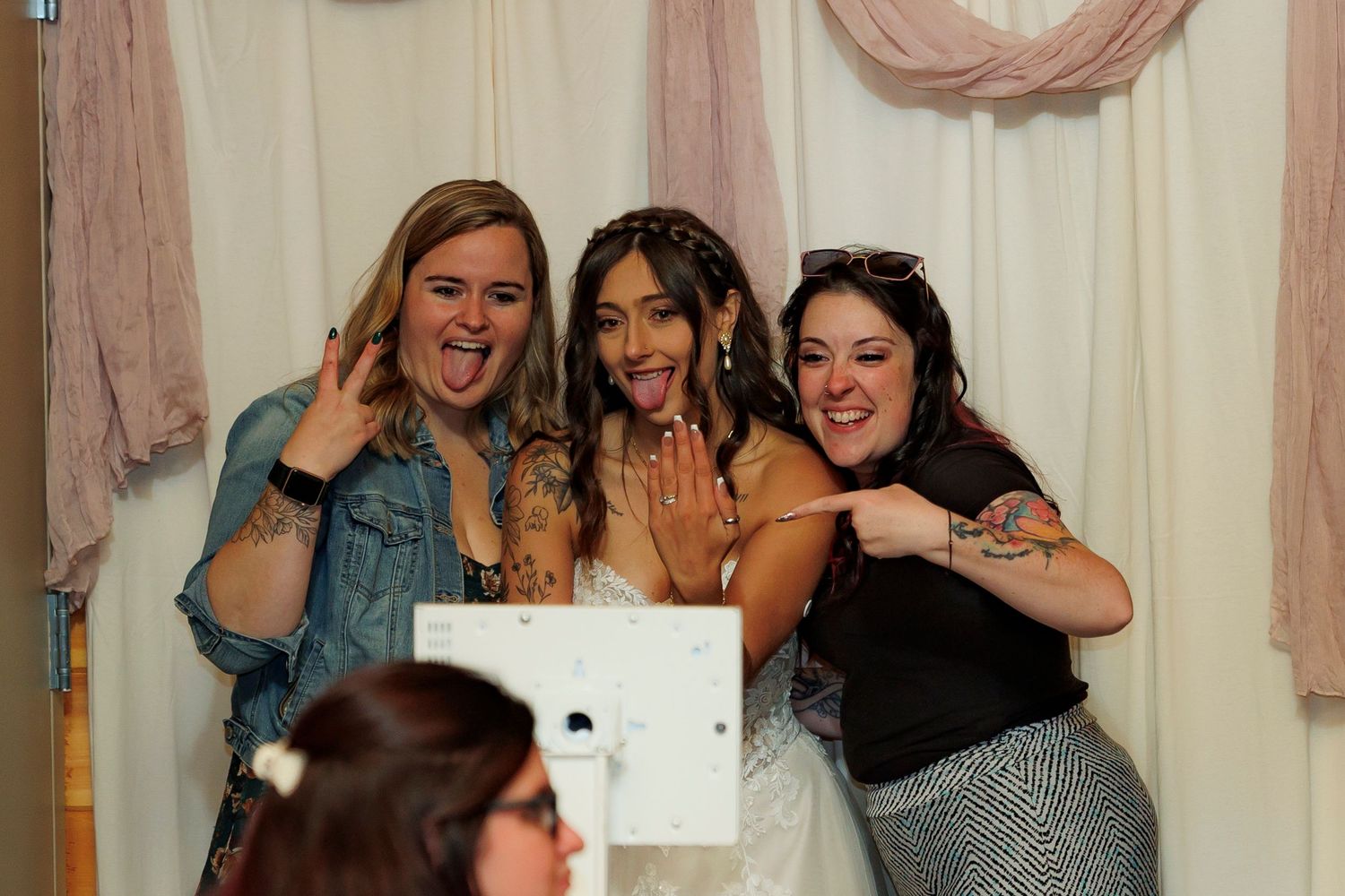 Group of women laugh and smile together at a celebration event with blush pink decor in the background.