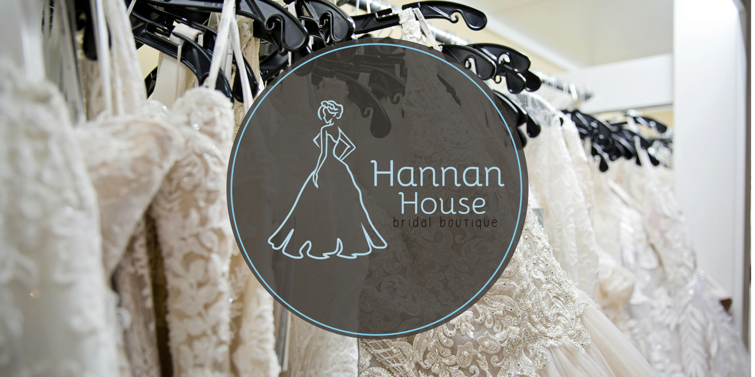 A row of elegant bridal gowns displayed on hangers with delicate lace details and flowing white fabrics.