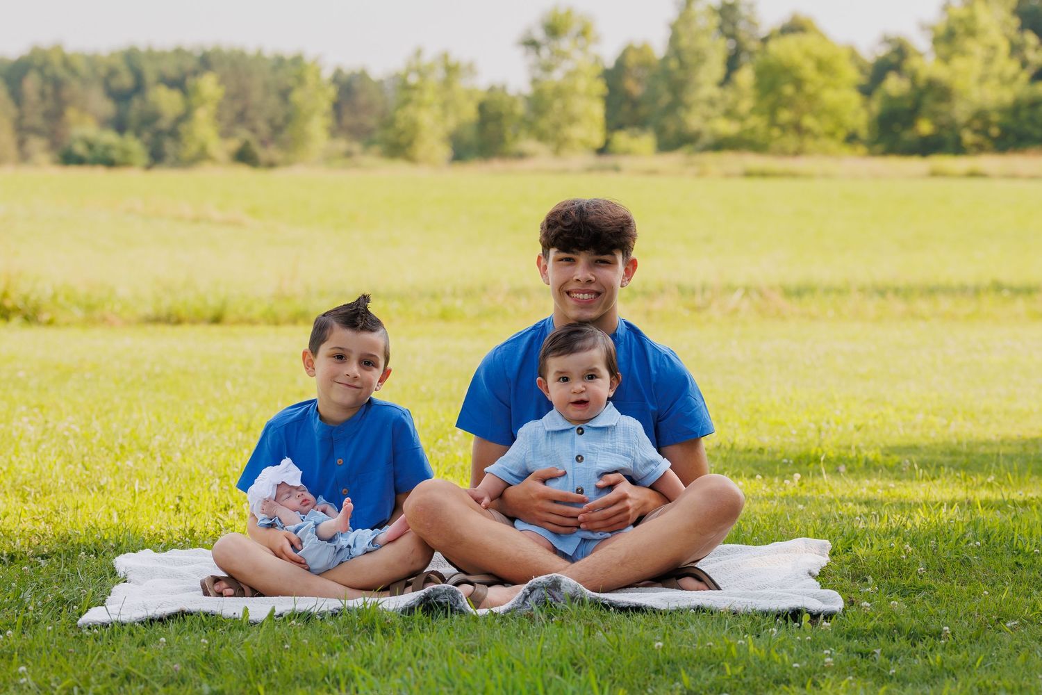 Families recline on blankets reading books together in a sunny green park on a beautiful summer day.