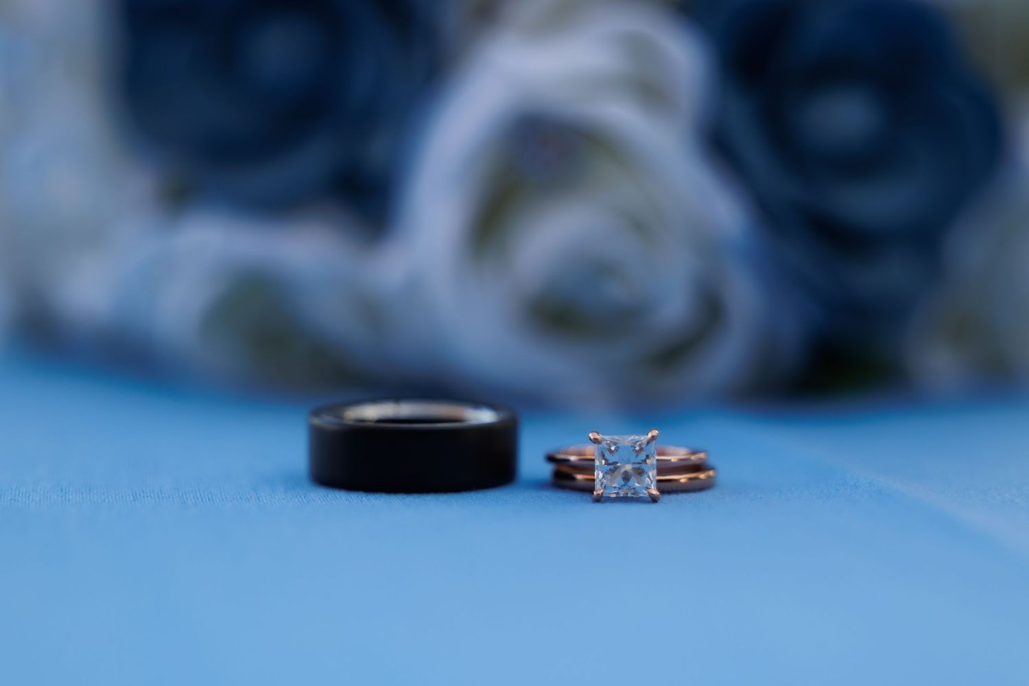 A sparkling diamond engagement ring photographed in a dreamy blue setting with shallow depth of field.