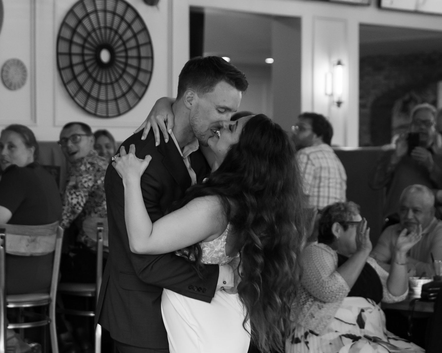 Couples dance together in an elegant ballroom with ornate circular ceiling details and wall sconces.