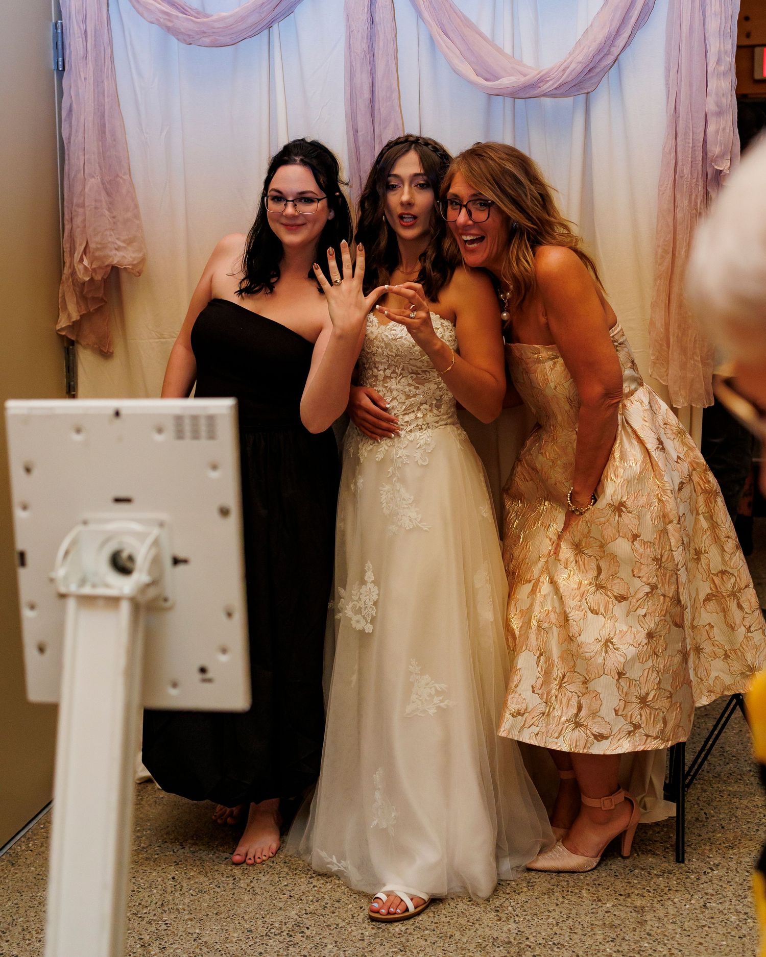 Bridesmaids in white and gold dresses laughing together during a wedding celebration.