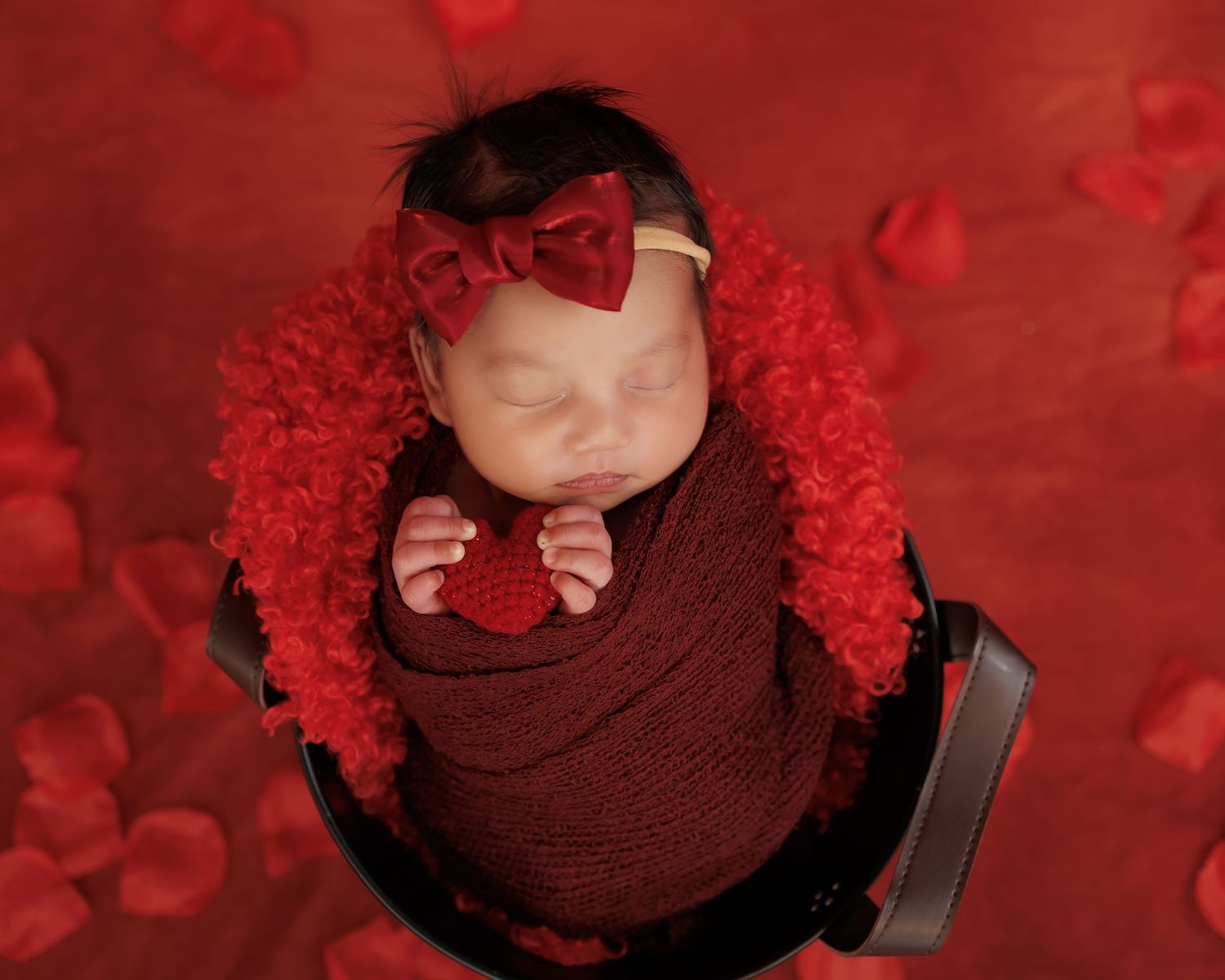 A creative portrait composition of someone wearing burgundy against a deep red bokeh background with dramatic lighting.