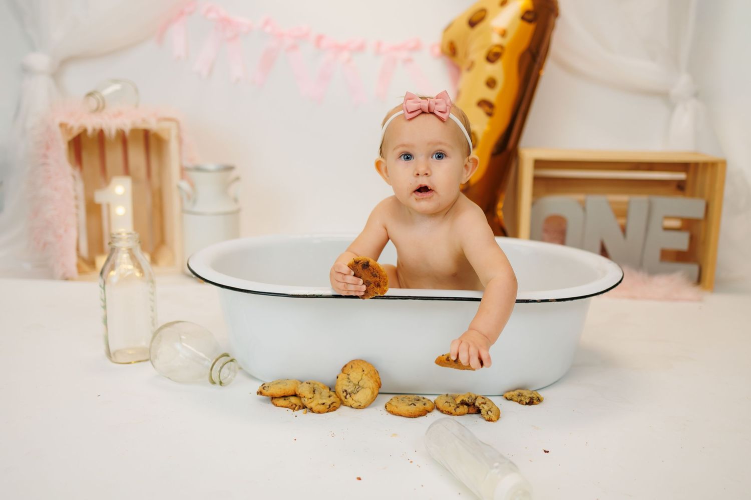 Baby in vintage-style bathtub with milk and chocolate chip cookies for creative milk and cookies themed photoshoot.