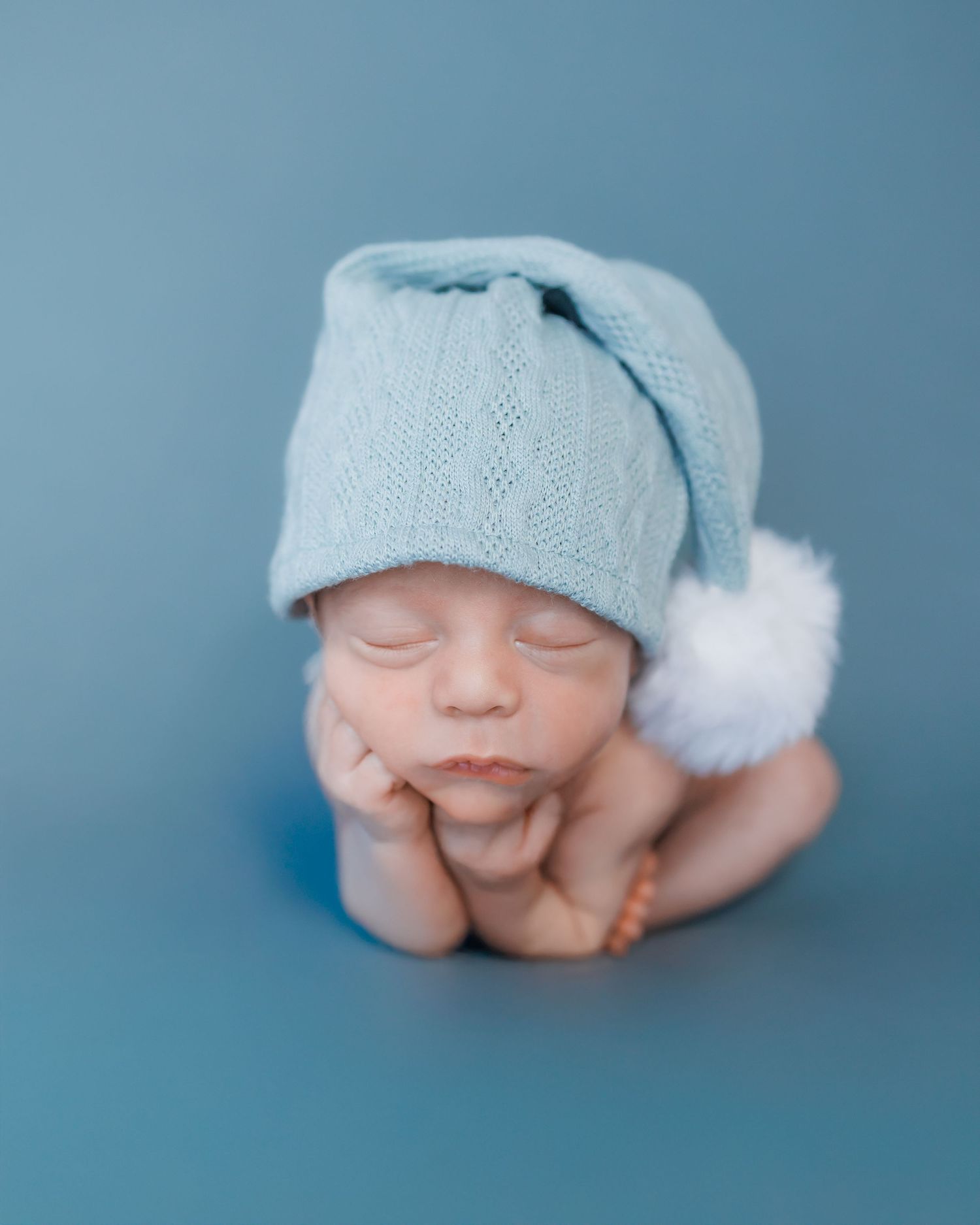 A series of monochromatic portraits showing close ups of a small baby wearing a light blue knitted cap.