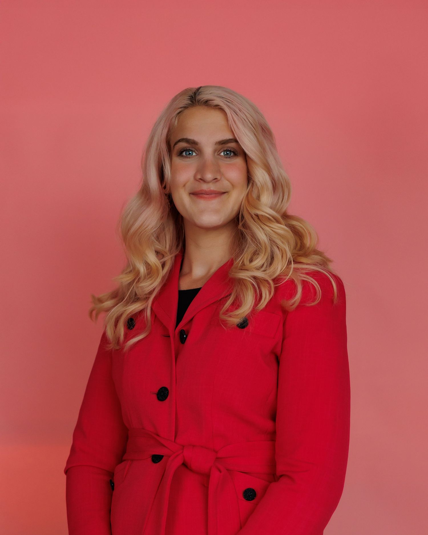 Four views of someone in a red coat with black buttons against a pink background showing different poses and angles.