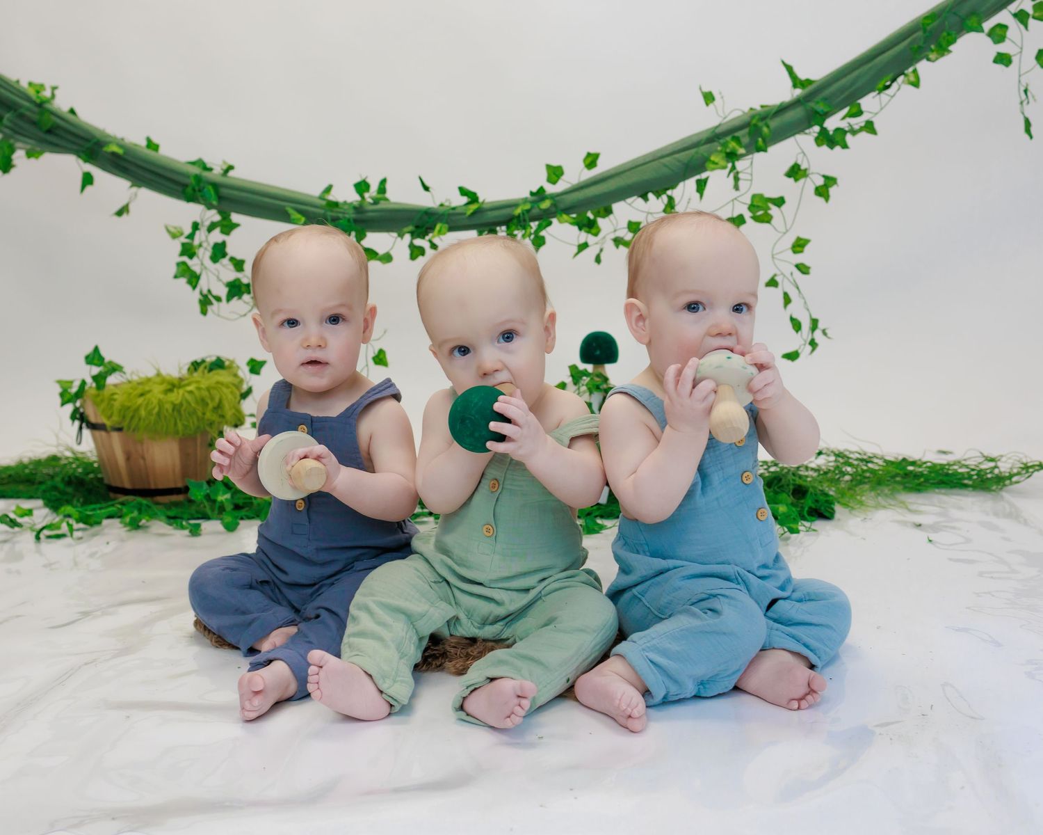 Multiple babies wearing coordinating blue and green outfits sit together in a series of connected photos.