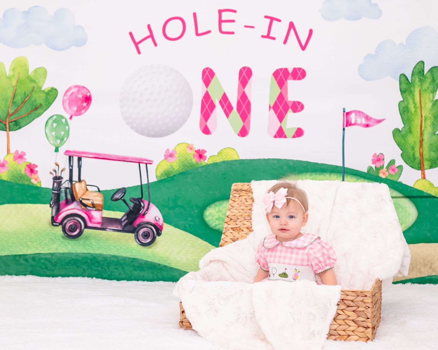 A baby plays in a whimsical garden setting with pink decorations and green watercolor scenery.