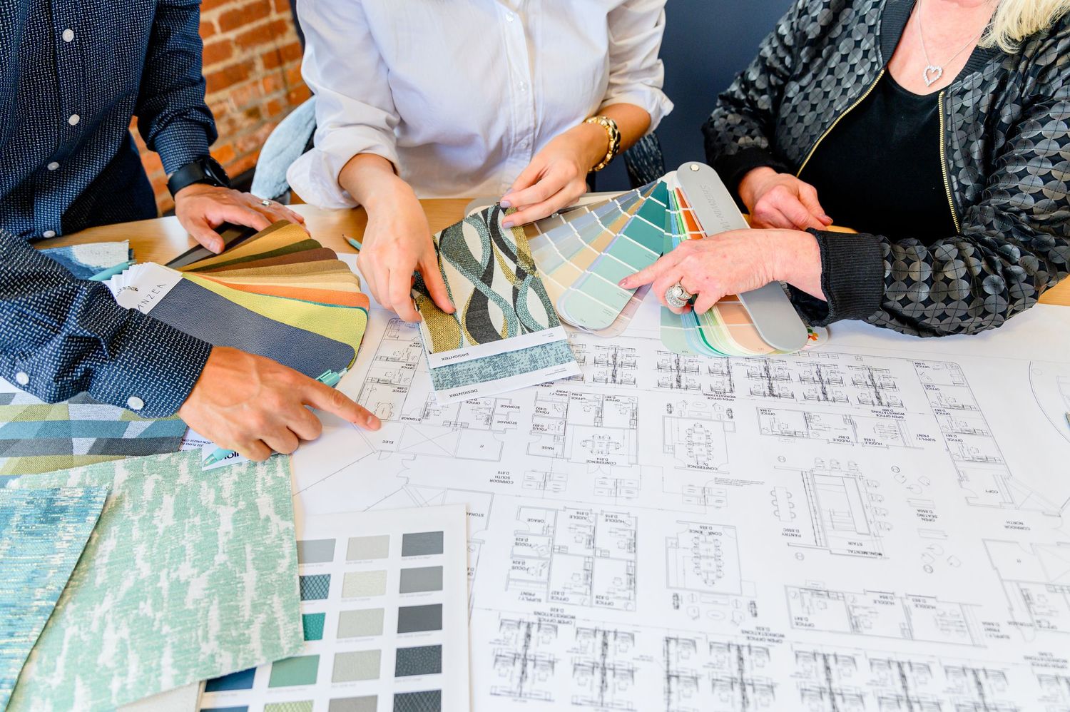 A group of people reviewing architectural blueprints and floor plans spread across a table during a project meeting.