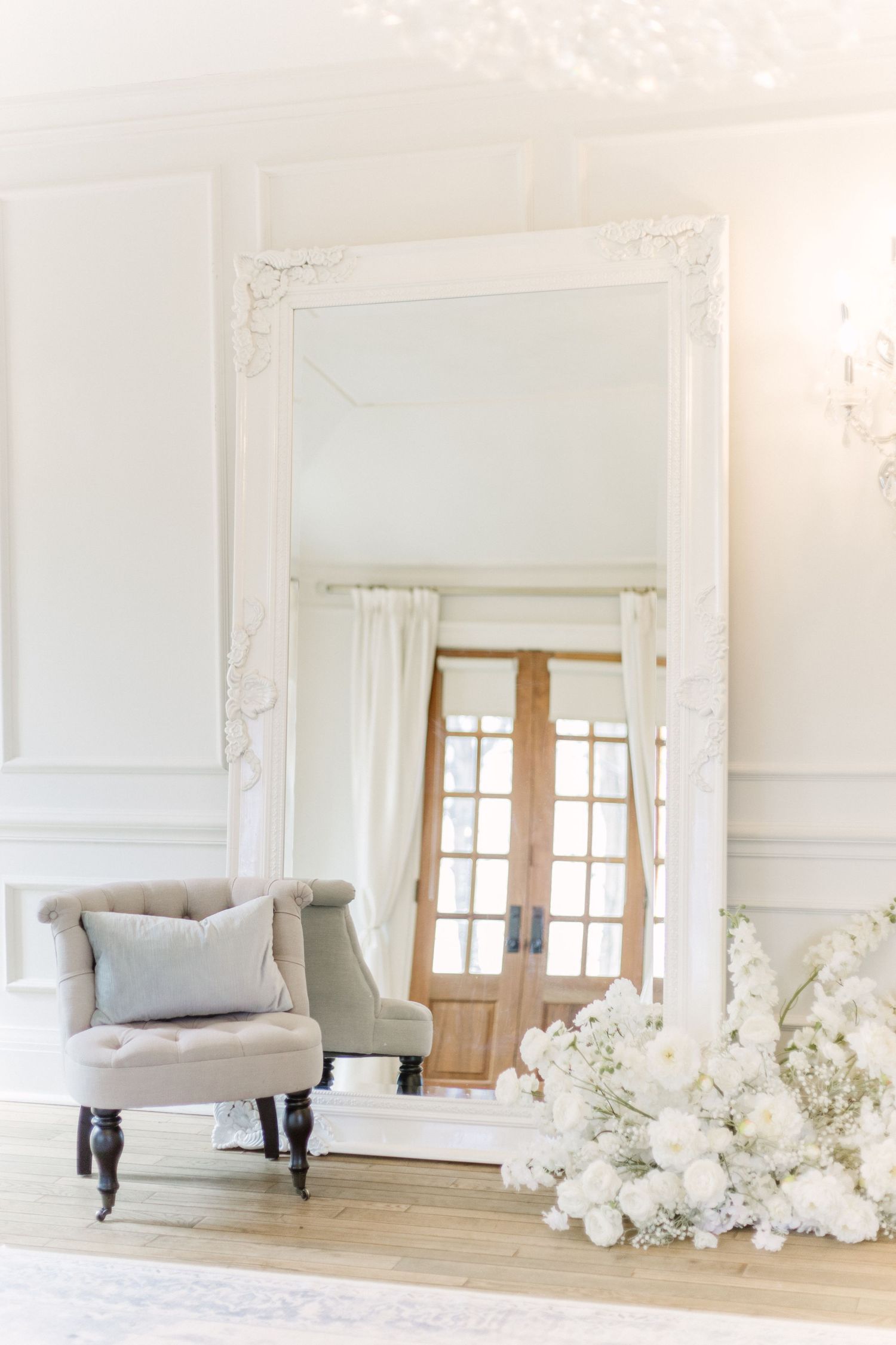 Bright white photography studio interior with classic chaise lounge and decorative wall trim details.