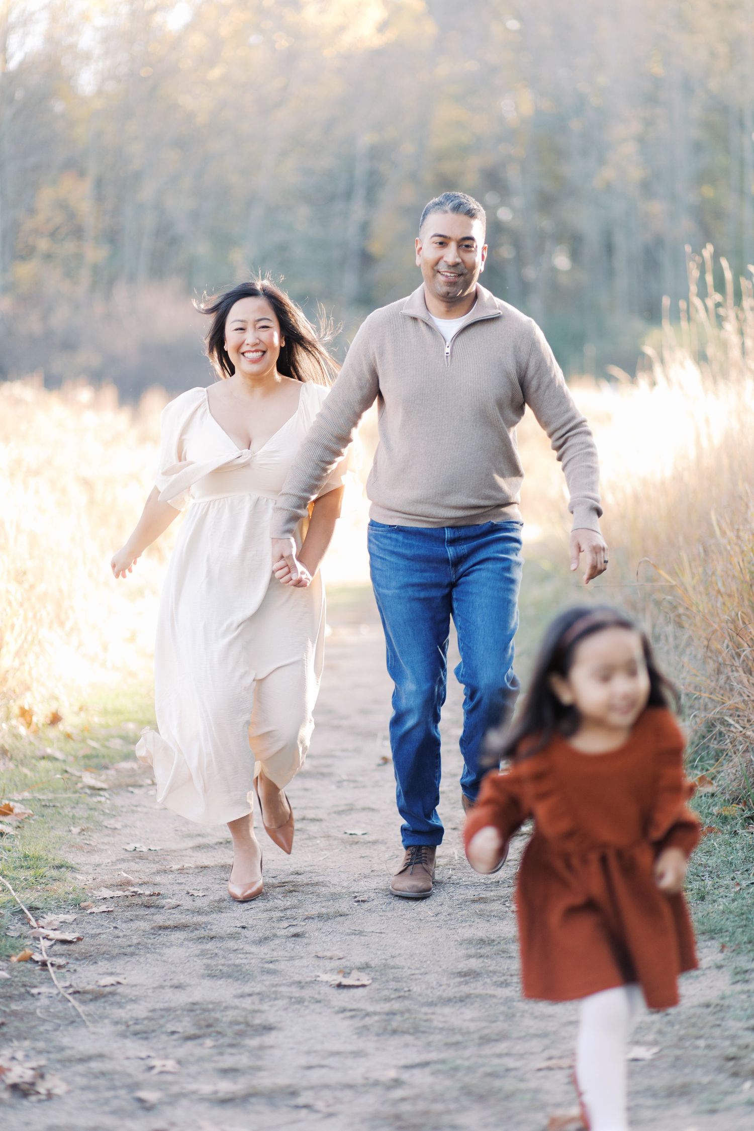 Family walks together on a nature trail during golden hour, creating playful motion-filled moments.