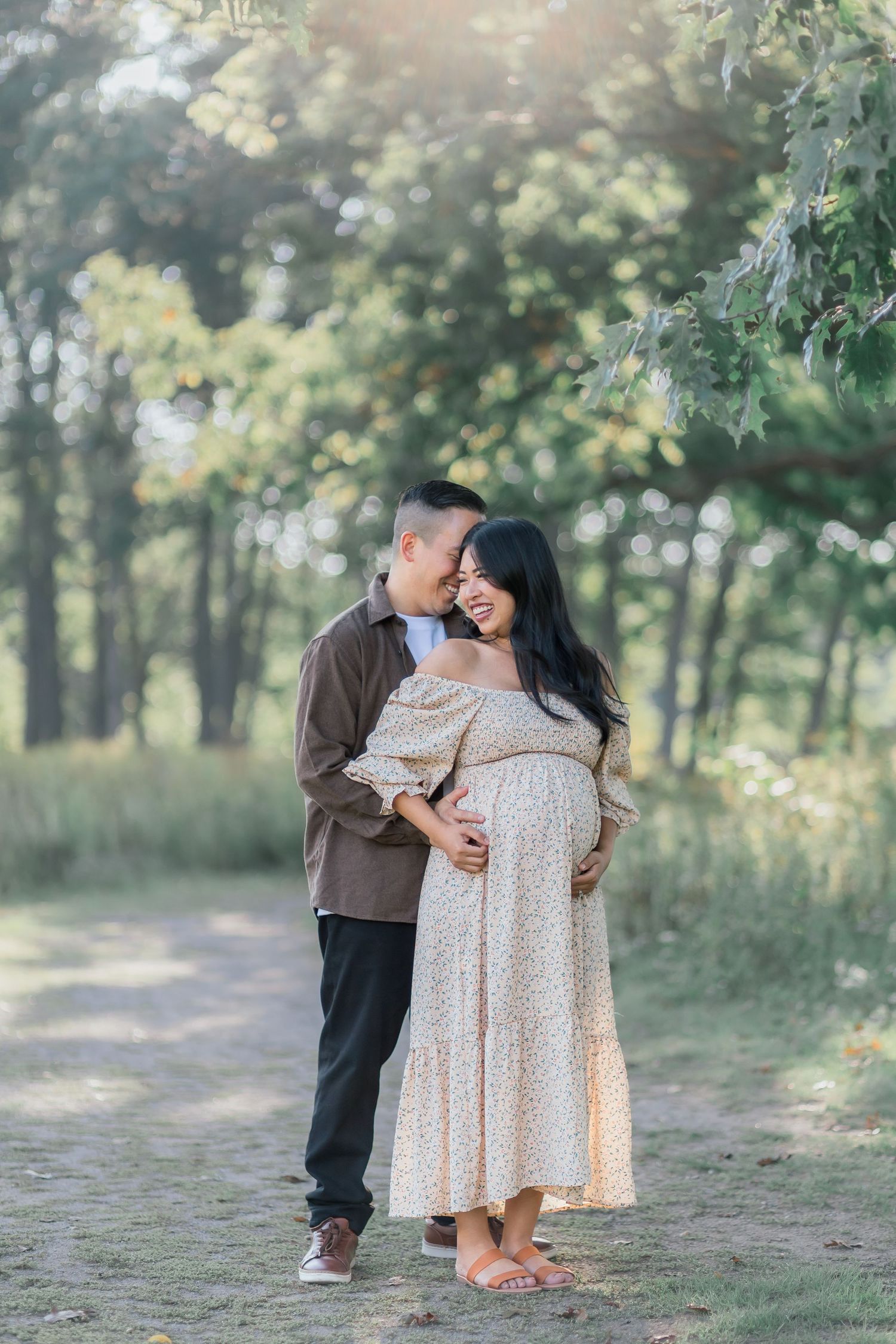 A couple shares tender moments together on a wooded path during an outdoor photo session.