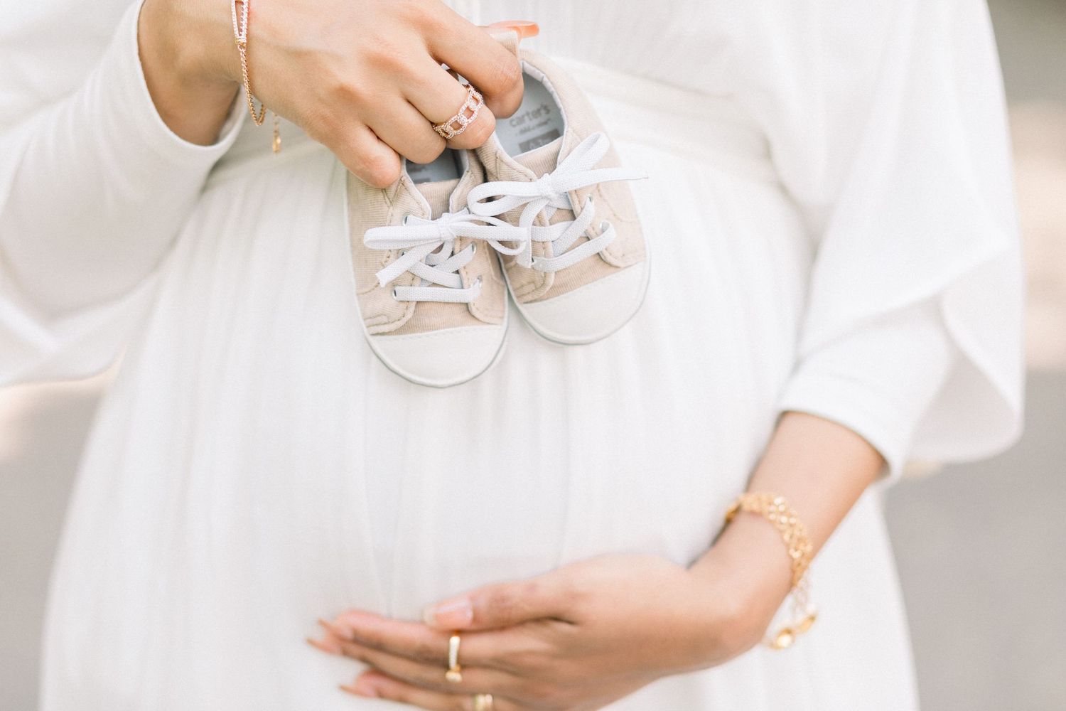 Close-up details of delicate white lace, fabric, and baby shoes create an elegant bridal composition.