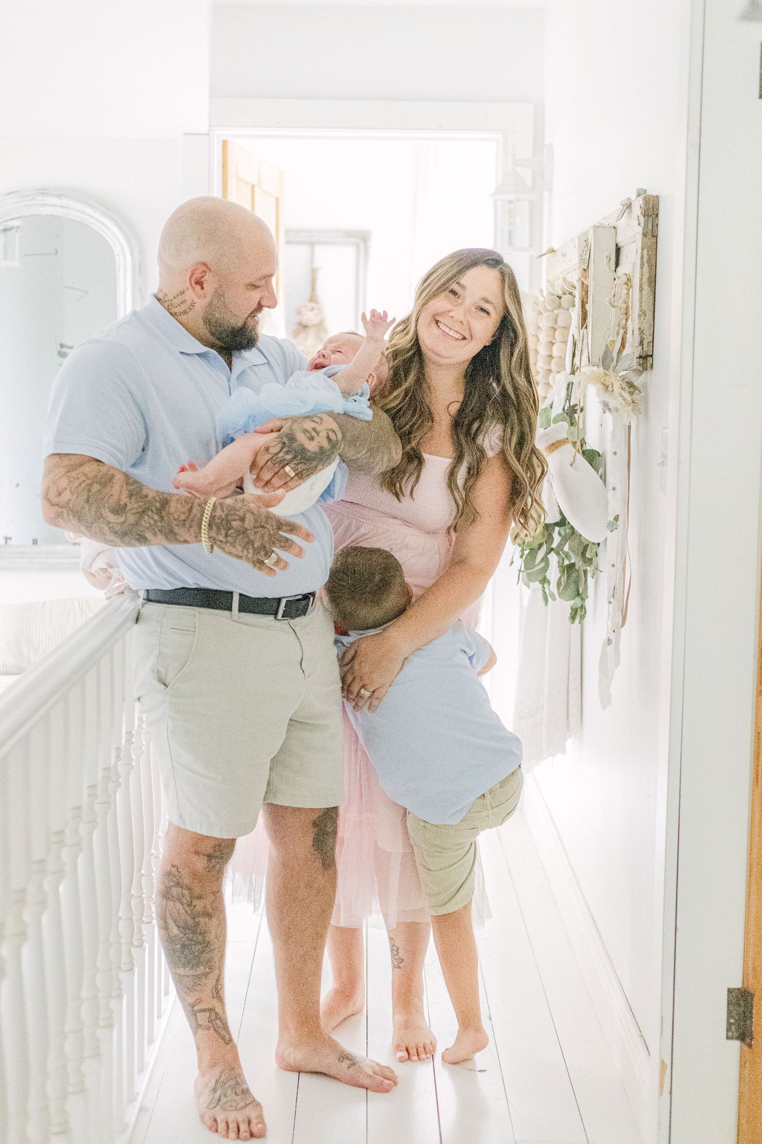 A bright and airy family photoshoot in a white hallway showing playful moments with a small child.