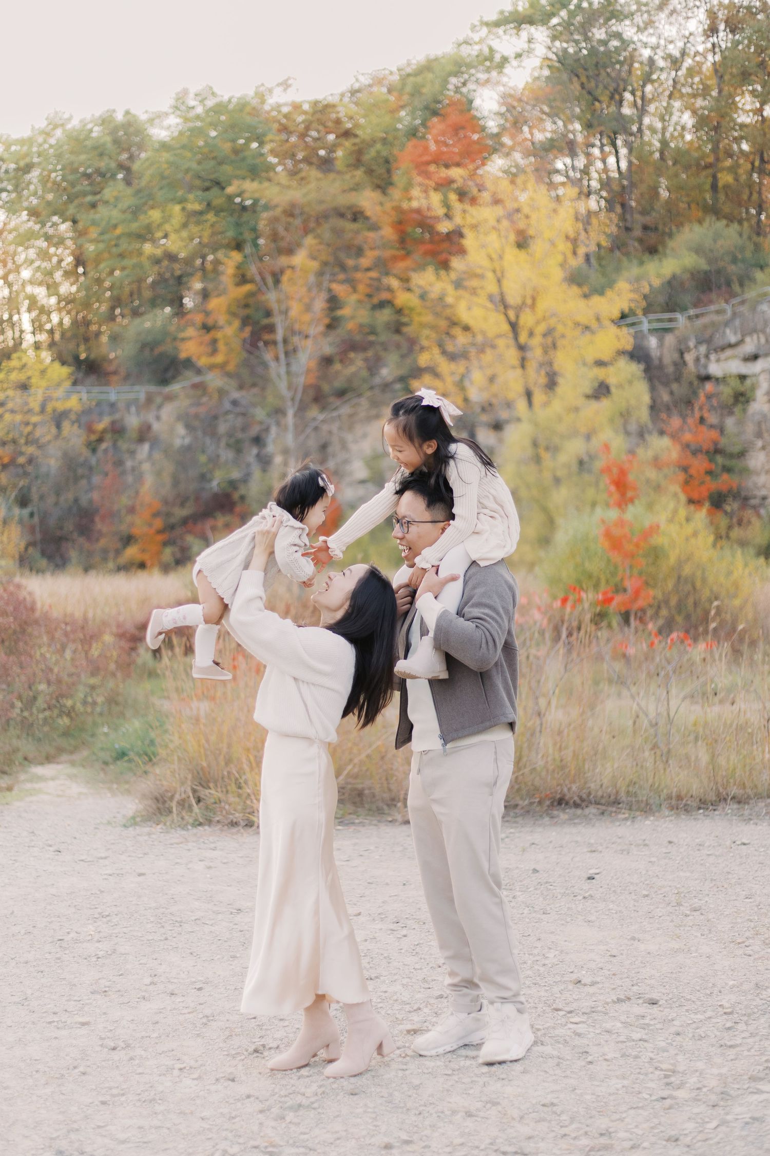 A couple dancing joyfully together on a sandy beach with autumn foliage in the background during golden hour.