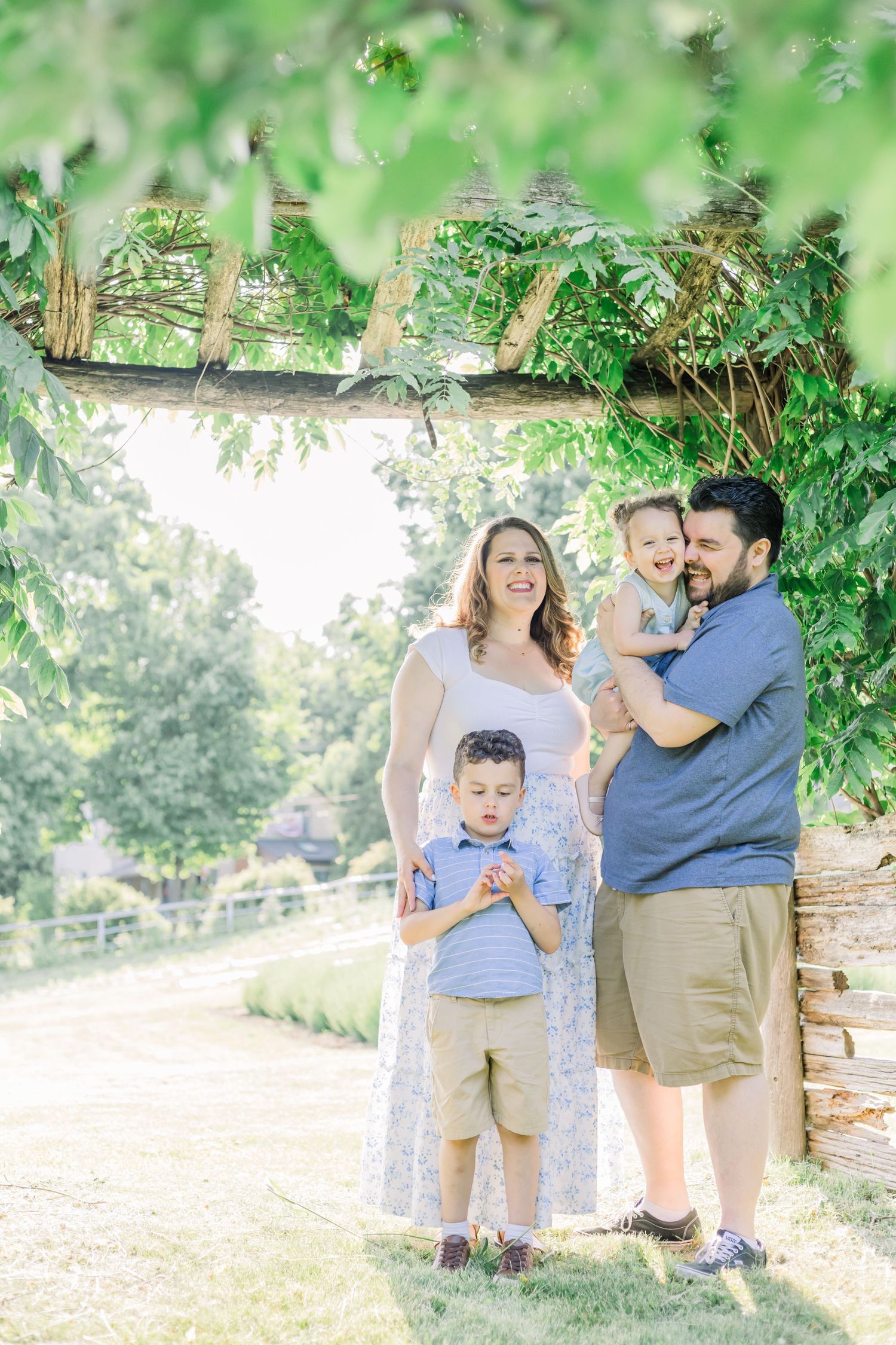 A family shares a tender moment together outdoors surrounded by lush greenery.