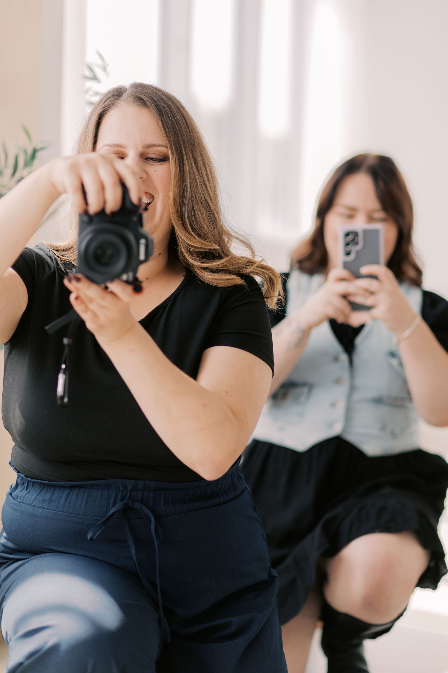 A series of photographers holding cameras in a row, wearing black and navy outfits in a bright studio setting.