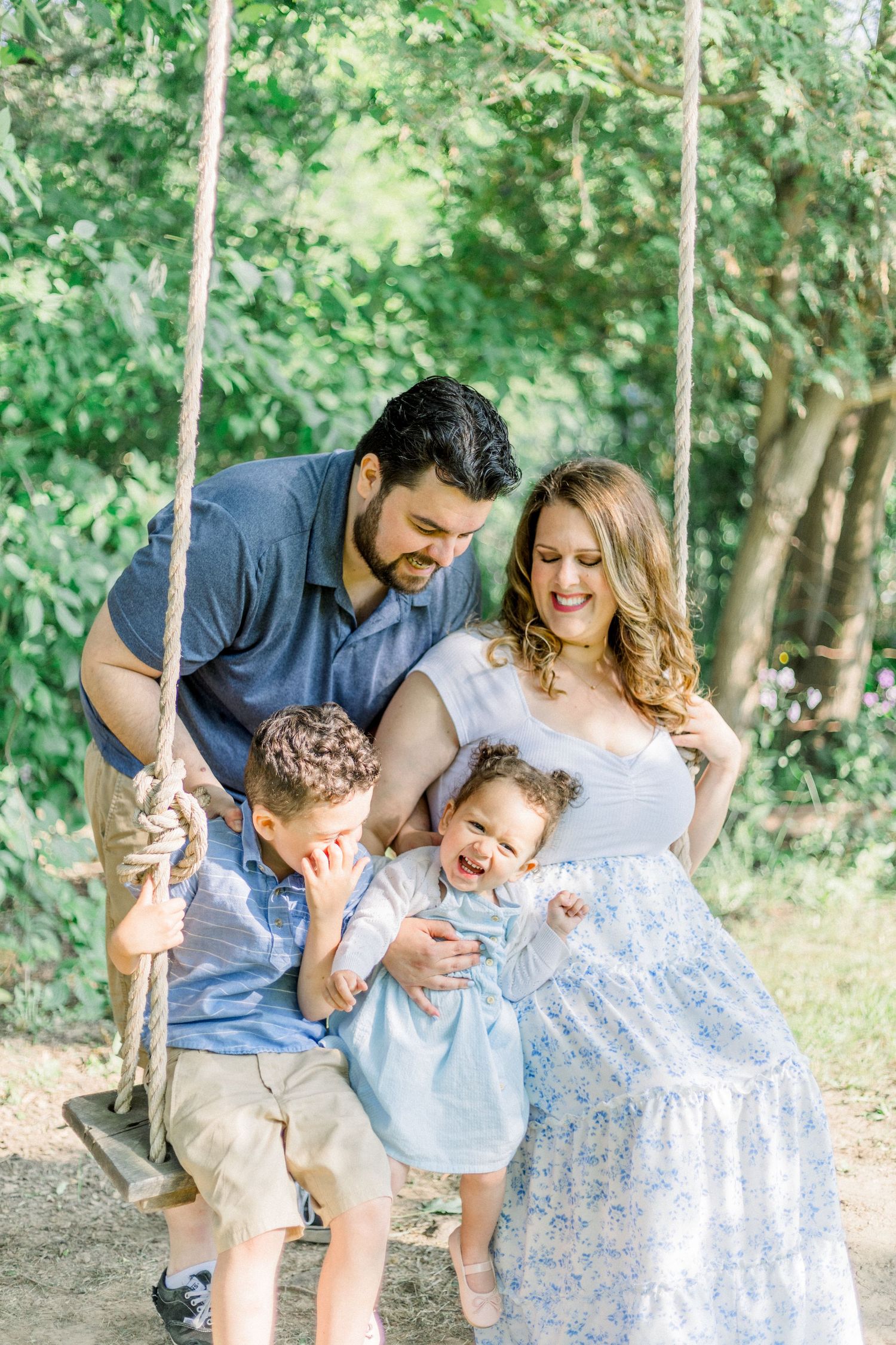 A family shares joyful moments together in a wooded outdoor setting, wearing coordinated blue and white outfits.