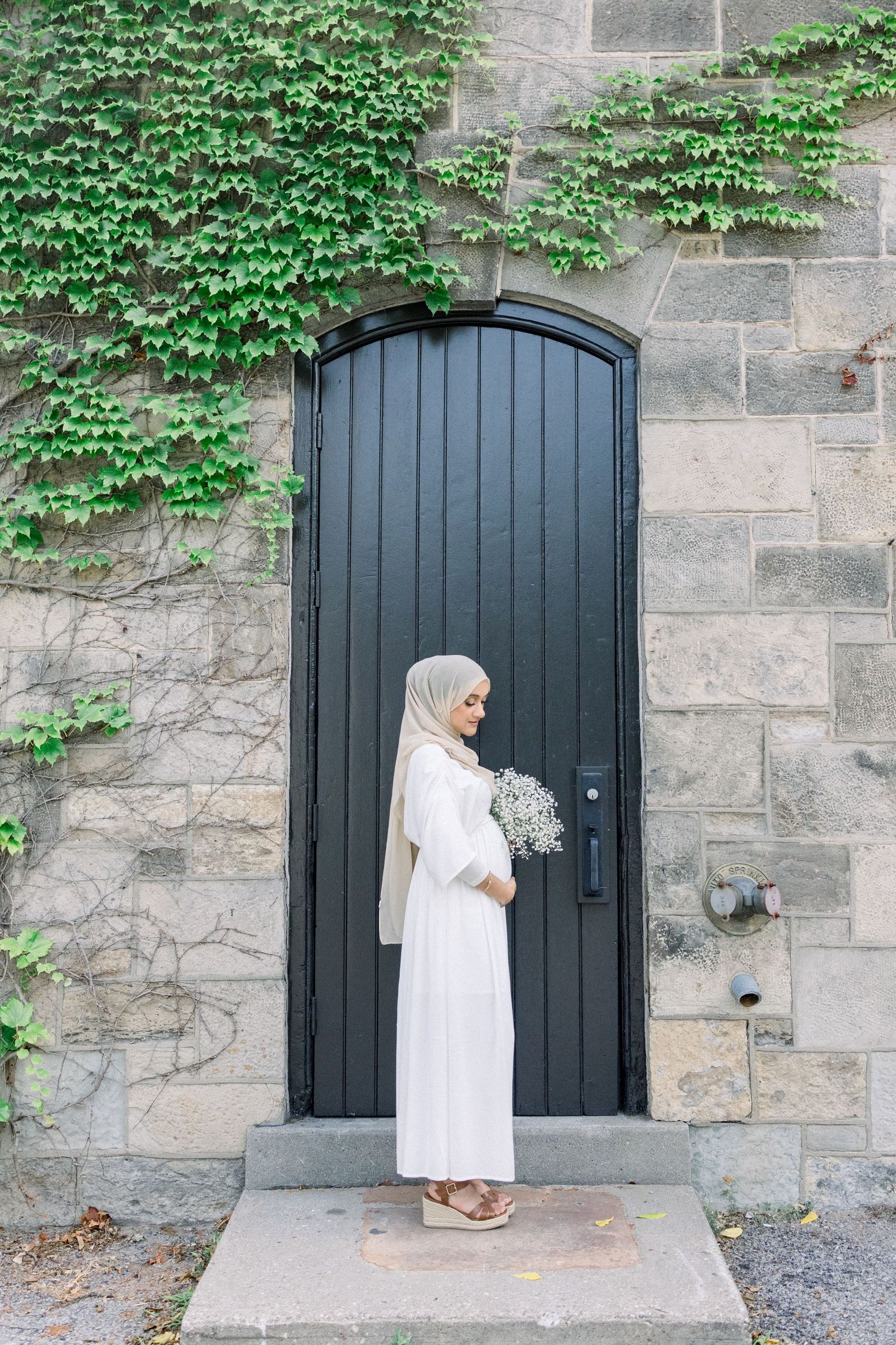 A series of photos showing someone in white dress and hijab standing by a dark arched door against a stone wall with ivy.
