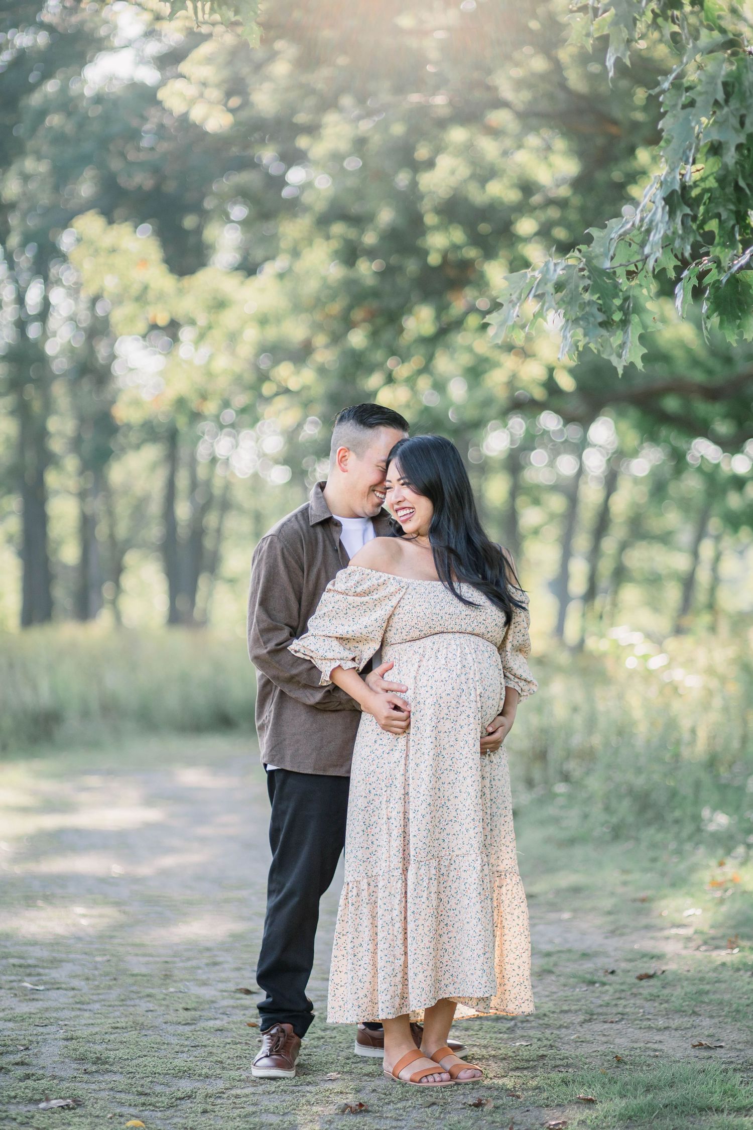 A couple shares tender moments together in a serene wooded setting with soft natural lighting and greenery.