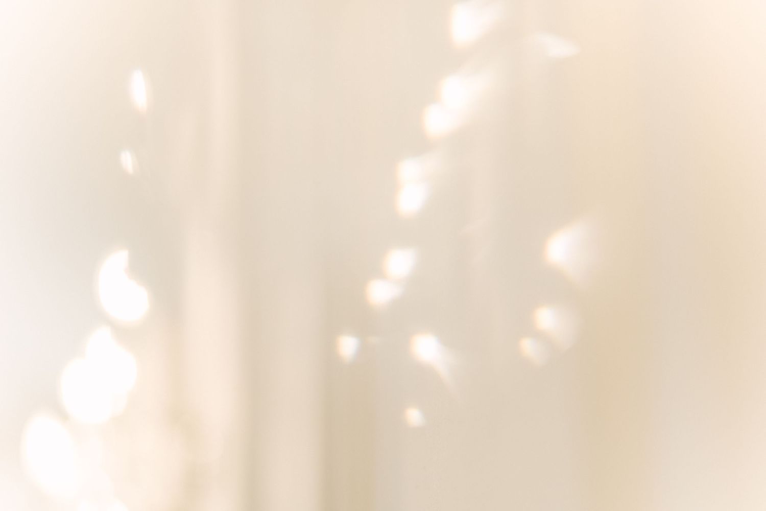 Abstract white and cream toned image with soft blurred bokeh lights creating a dreamy ethereal effect.